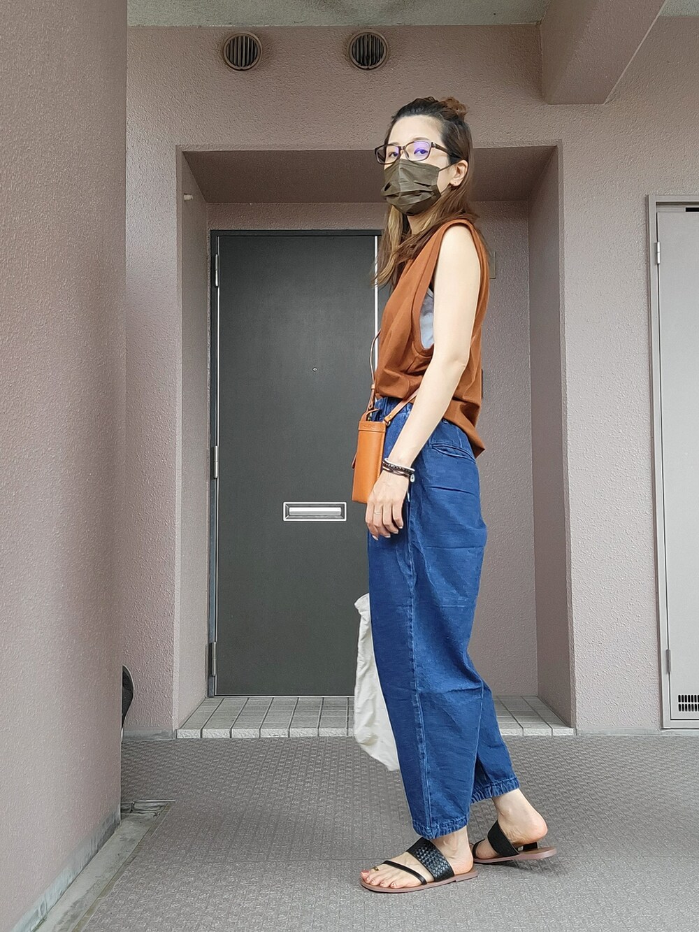 ブルー系のパンツ、イエロー系のショルダーバッグ、ブラウン系のトップスを着用したレディースの夏コーディネートの2枚目の写真