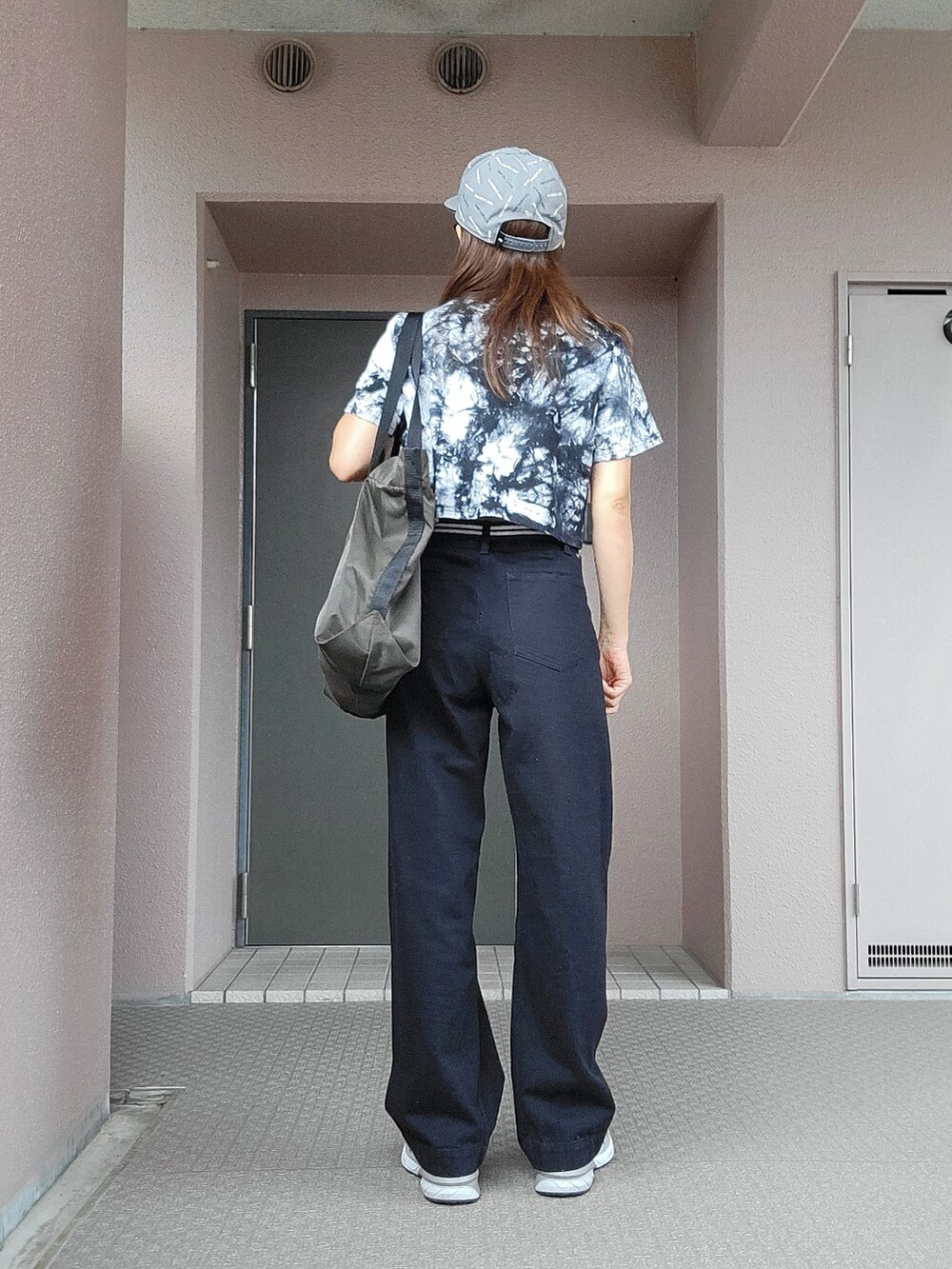 ブラック系のデニムパンツ、グリーン系のトートバッグ、ブラック系のTシャツ/カットソーを着用したレディースの夏コーディネートの3枚目の写真