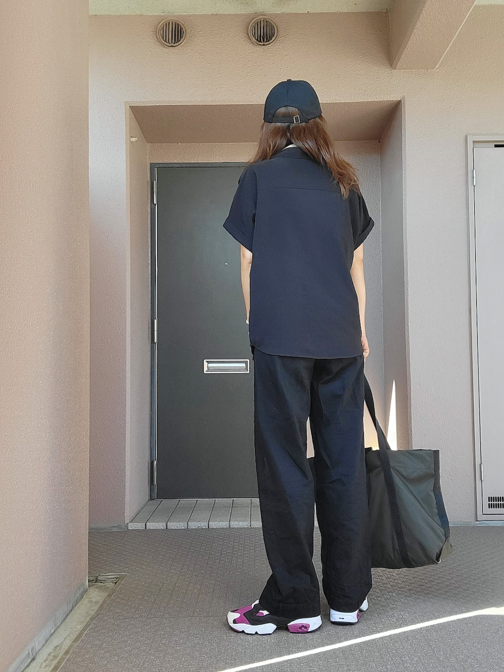 ブラック系のデニムパンツ、グリーン系のトートバッグ、パープル系のスニーカーを着用したレディースの夏コーディネートの3枚目の写真