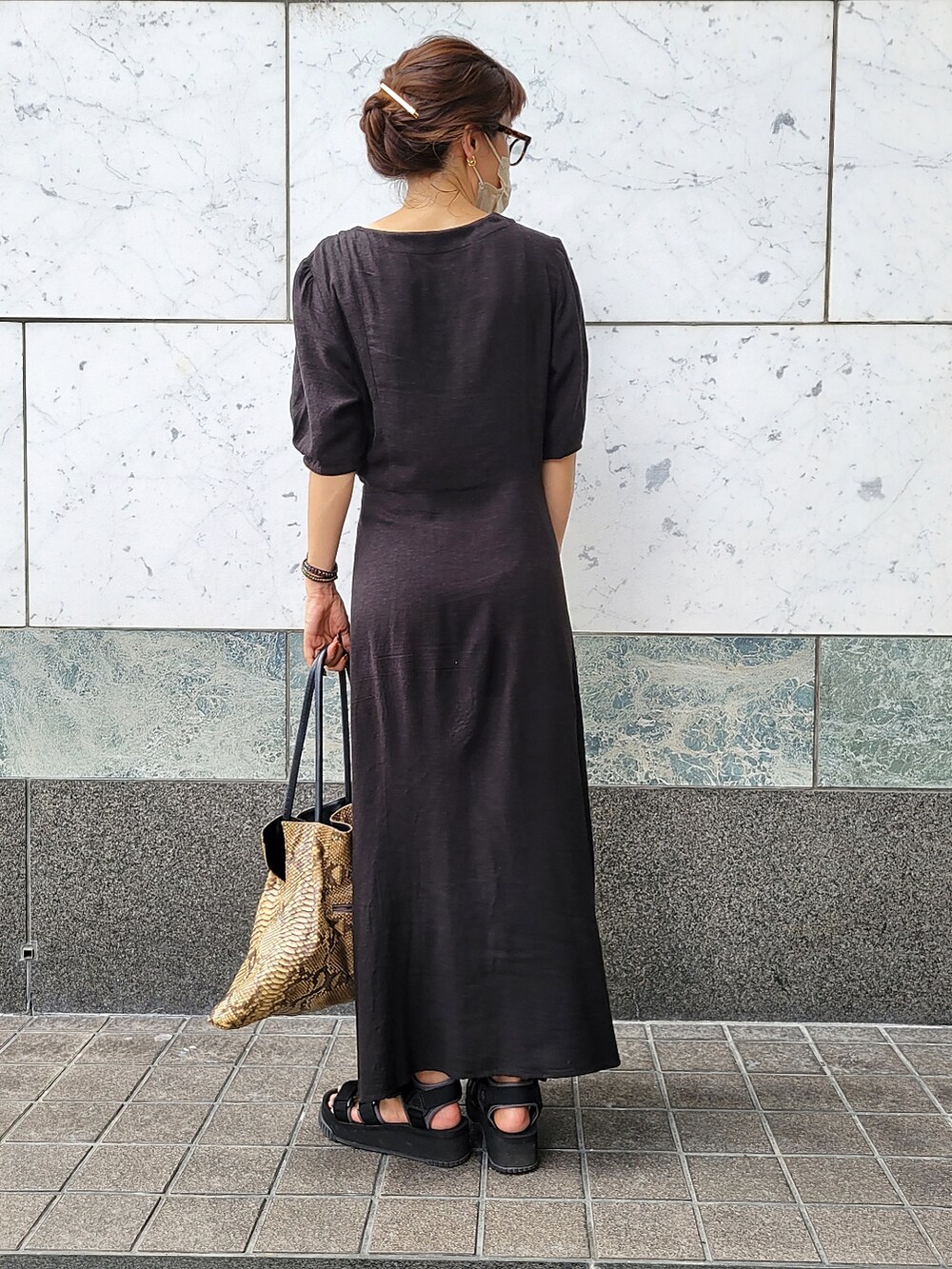 ブラウン系のトートバッグ、ブラック系のワンピース、ブラック系のサンダルを着用したレディースの秋コーディネートの2枚目の写真