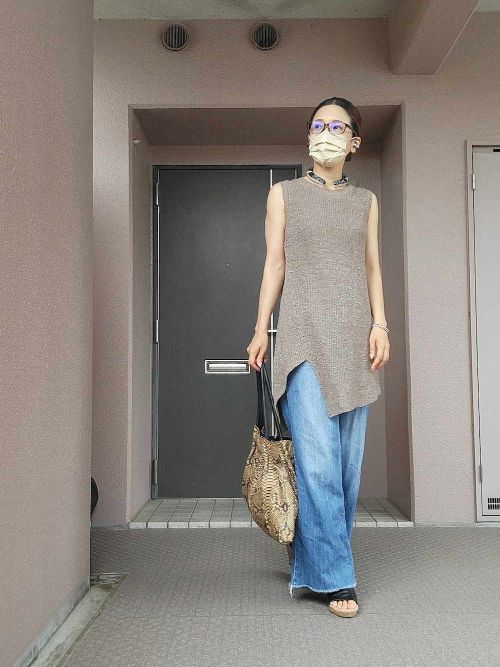 ブラウン系のトートバッグ、ブラウン系のニット/セーター、ブルー系のデニムパンツを着用したレディースの夏コーディネートの3枚目の写真