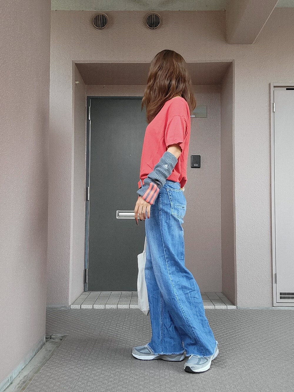 ブルー系のデニムパンツ、ホワイト系のエコバッグ/サブバッグ、グレー系のスニーカーを着用したレディースの秋コーディネートの2枚目の写真