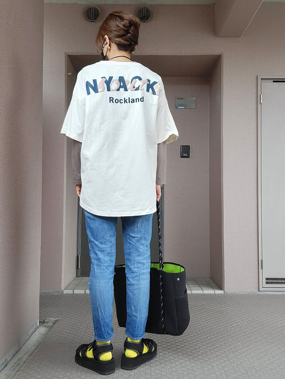 ブラック系のトートバッグ、ブルー系のデニムパンツ、ブラック系のサンダルを着用したレディースの春コーディネートの2枚目の写真