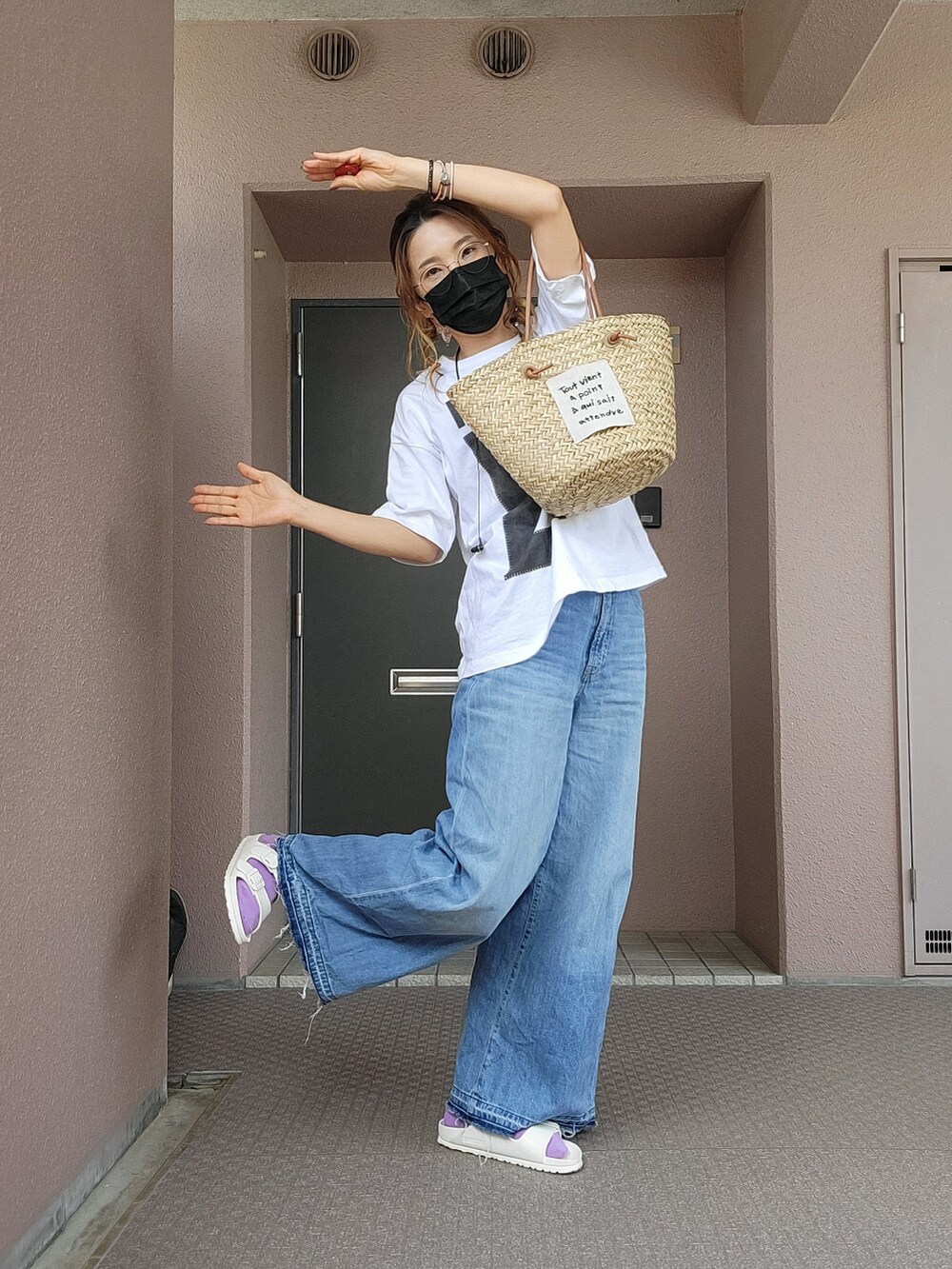 ベージュ系のかごバッグ、ブルー系のデニムパンツ、ホワイト系のサンダルを着用したレディースの春コーディネートの4枚目の写真