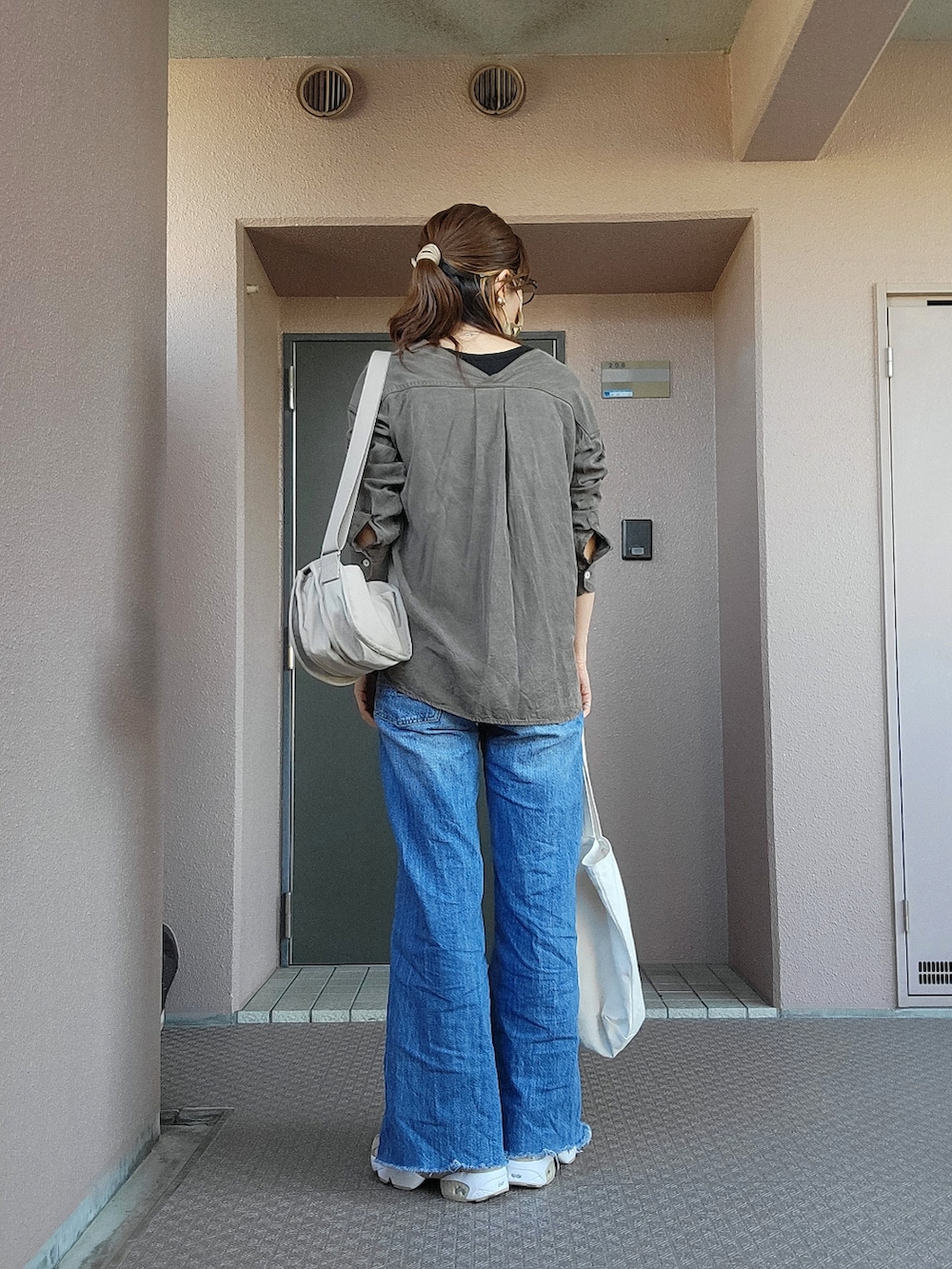 ブルー系のデニムパンツ、ホワイト系のエコバッグ/サブバッグ、ベージュ系のショルダーバッグを着用したレディースの春コーディネートの2枚目の写真