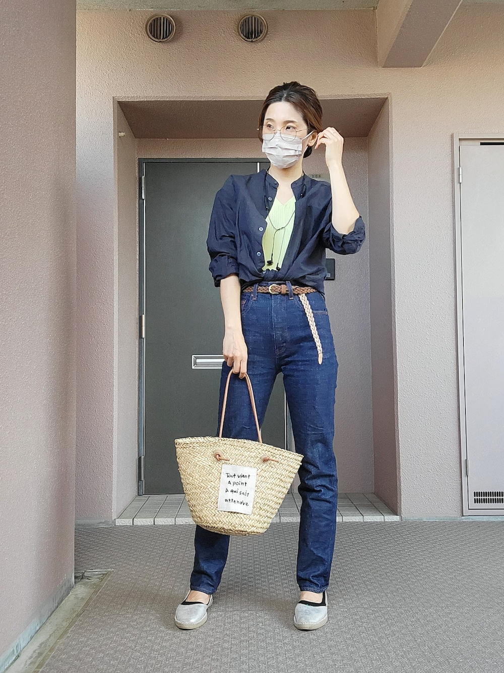 ベージュ系のかごバッグ、ブルー系のデニムパンツ、シルバー系のスリッポンを着用したレディースの春コーディネートの2枚目の写真