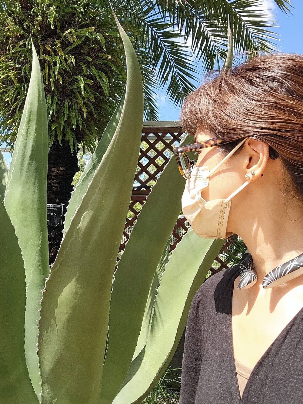 ブラウン系のトートバッグ、ブラック系のワンピース、ブラック系のサンダルを着用したレディースの秋コーディネートの3枚目の写真