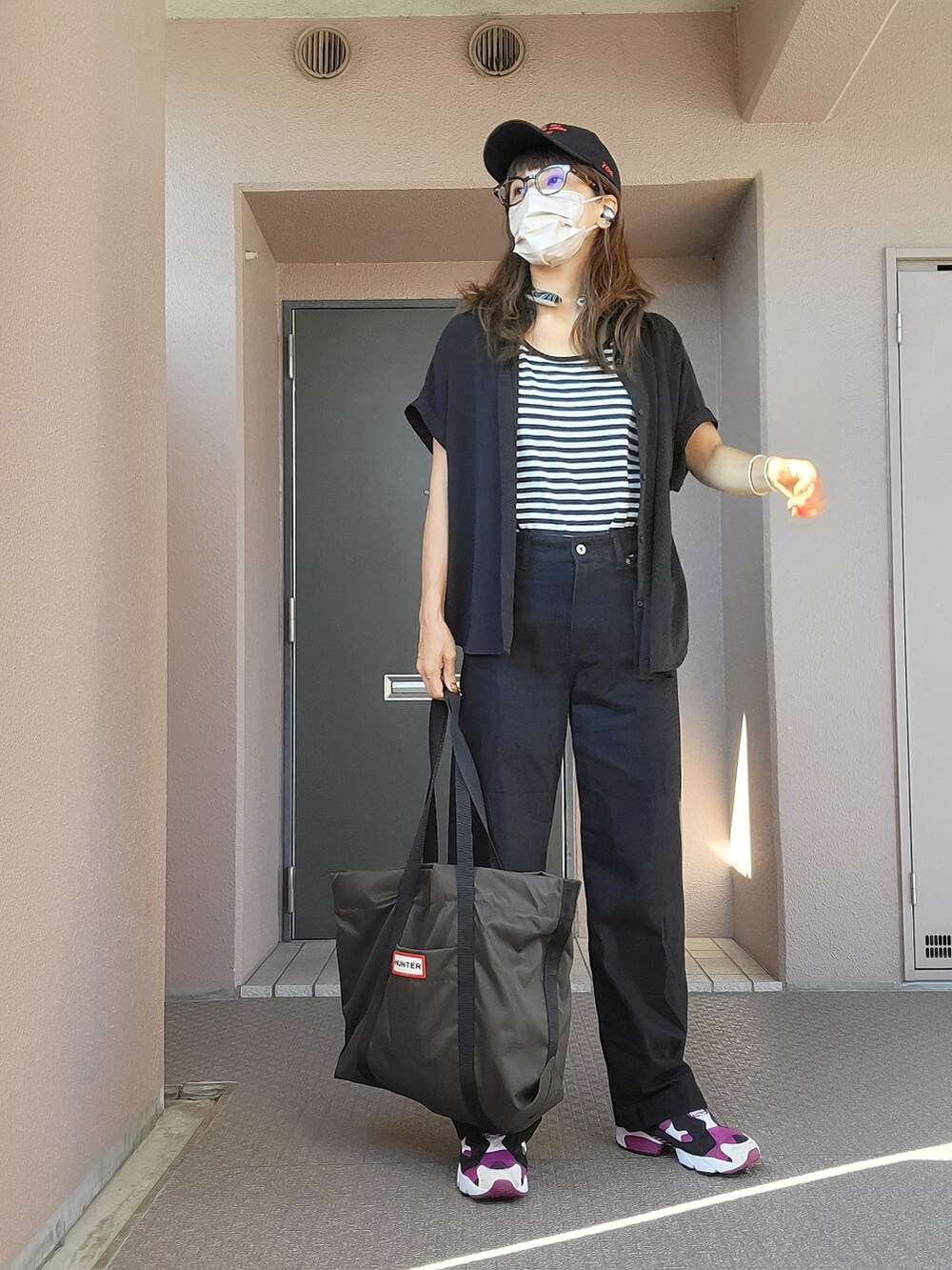 ブラック系のデニムパンツ、グリーン系のトートバッグ、パープル系のスニーカーを着用したレディースの夏コーディネートの2枚目の写真