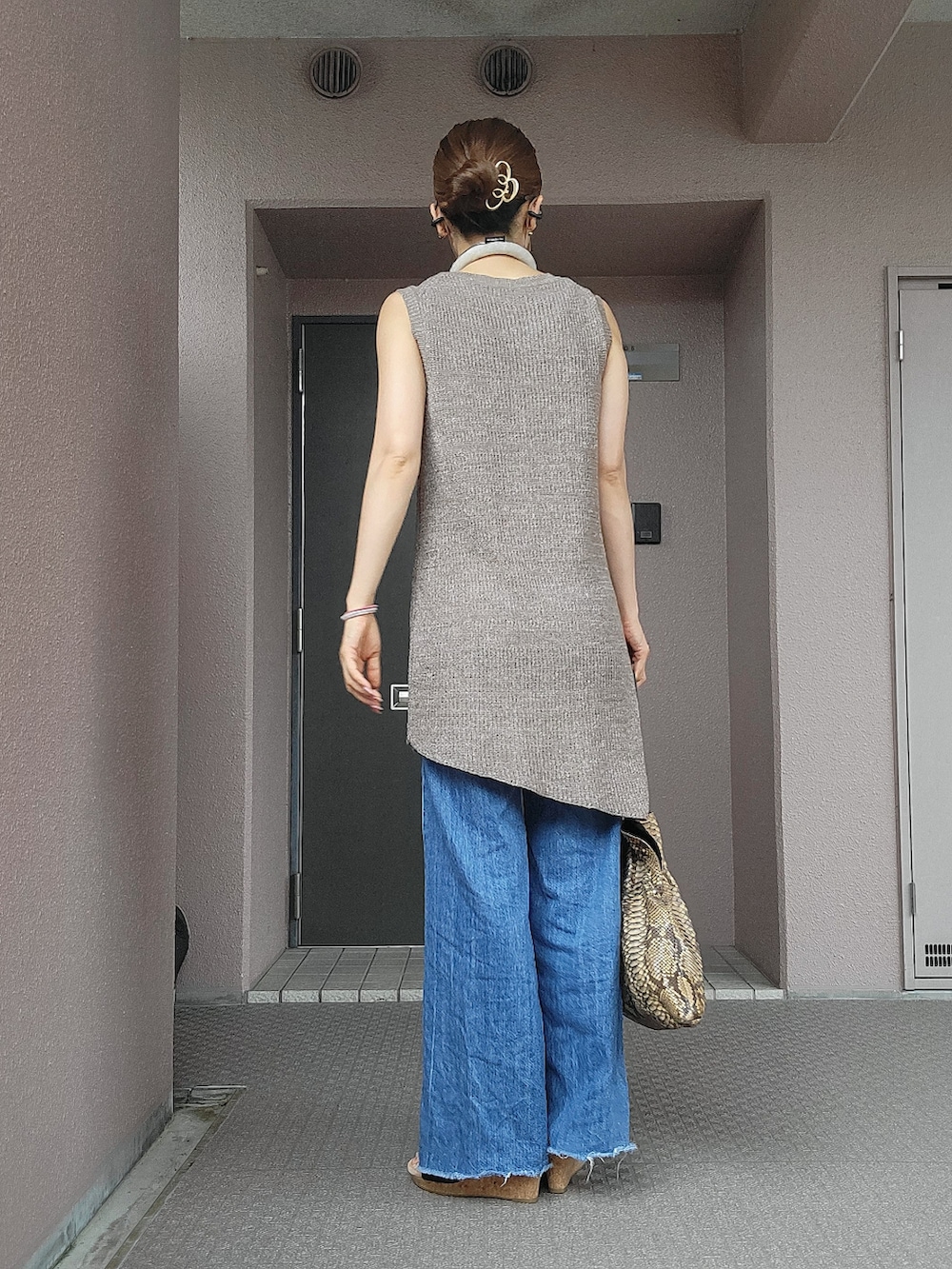 ブラウン系のトートバッグ、ブラウン系のニット/セーター、ブルー系のデニムパンツを着用したレディースの夏コーディネートの2枚目の写真