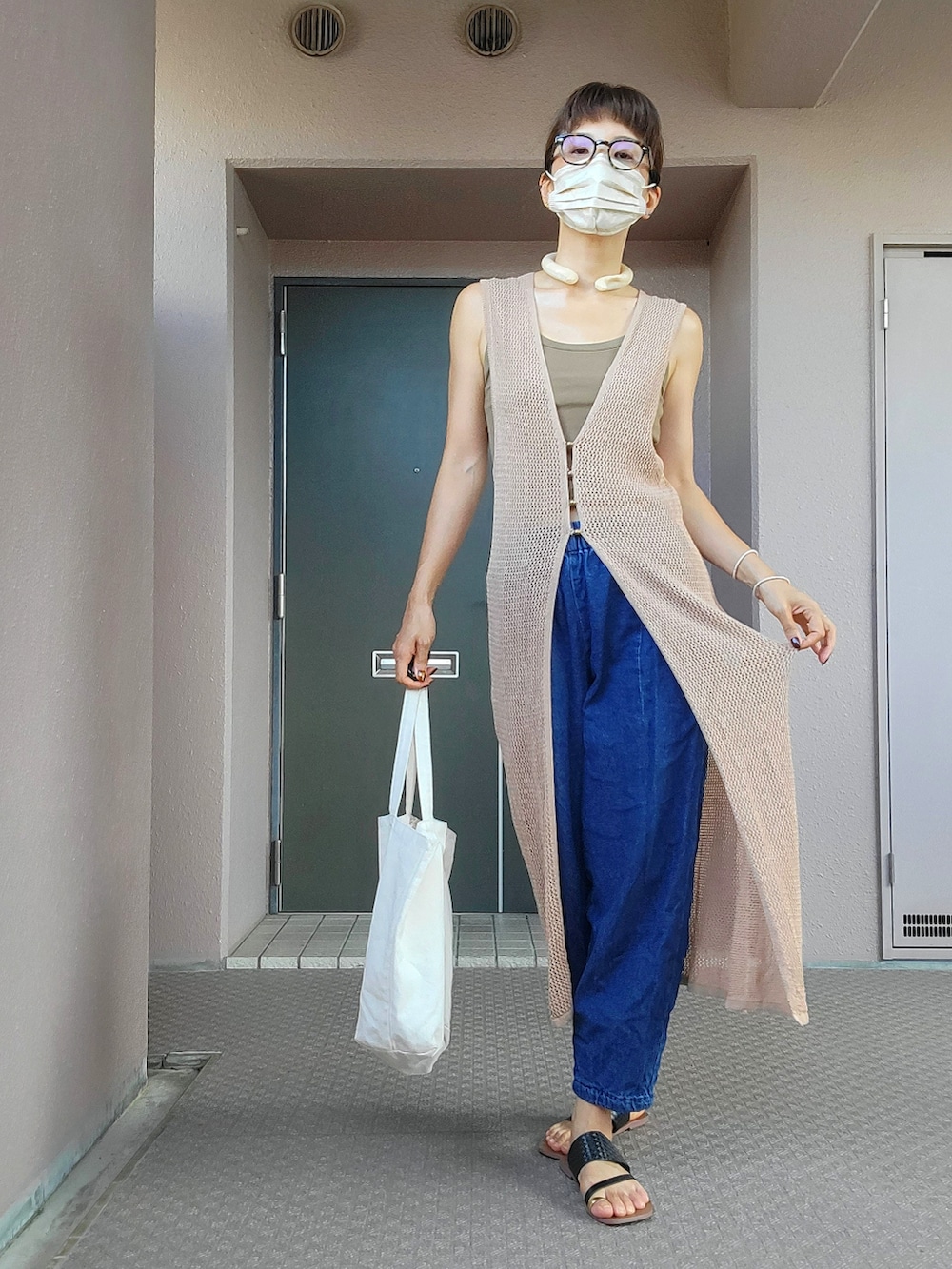 ブラック系のサンダル、ブルー系のパンツ、ベージュ系のワンピースを着用したレディースの夏コーディネートの2枚目の写真