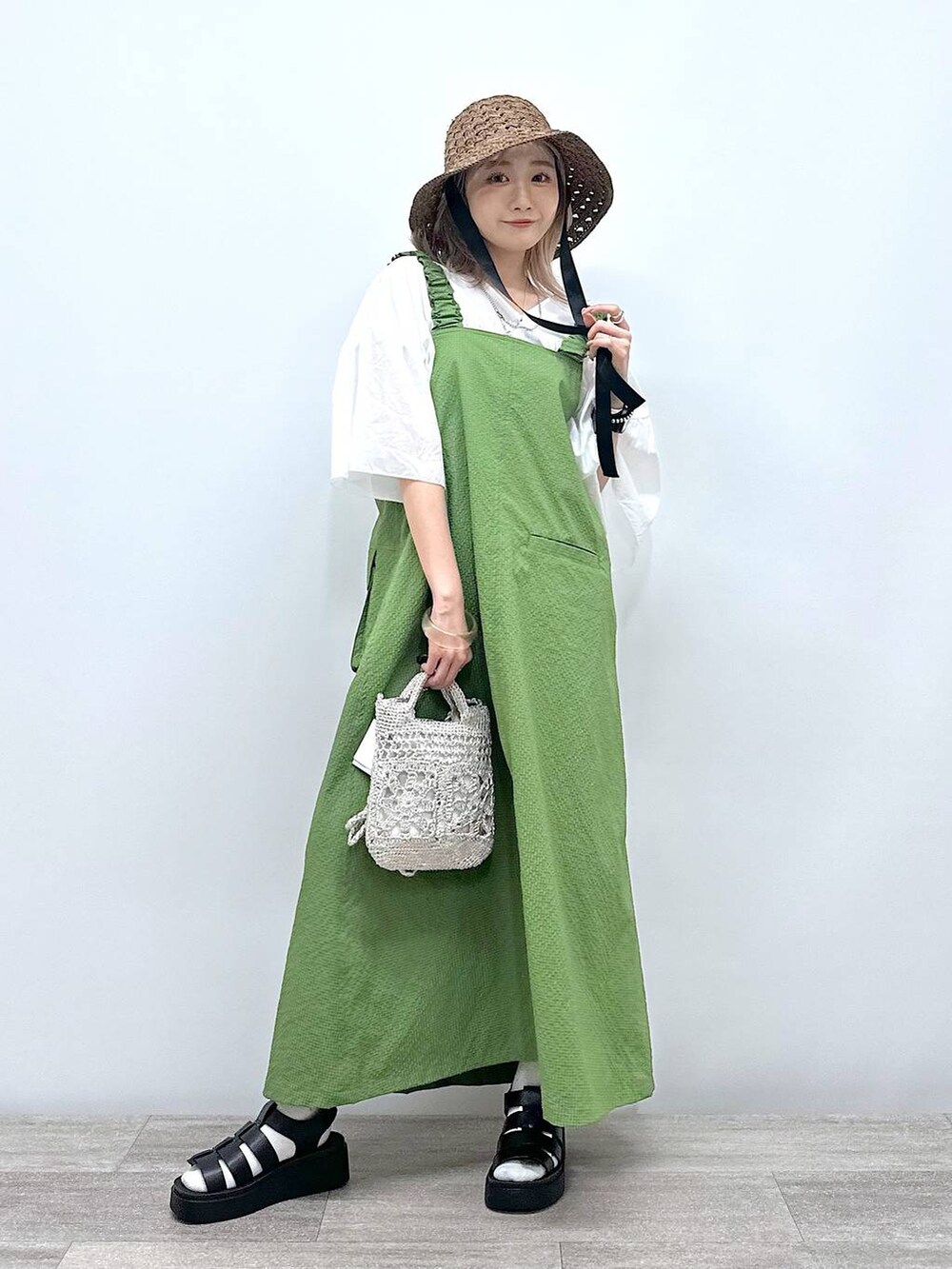 グレー系のショルダーバッグ、ブラック系のサンダル、グリーン系のジャンパースカートを着用したレディースの夏コーディネートの5枚目の写真