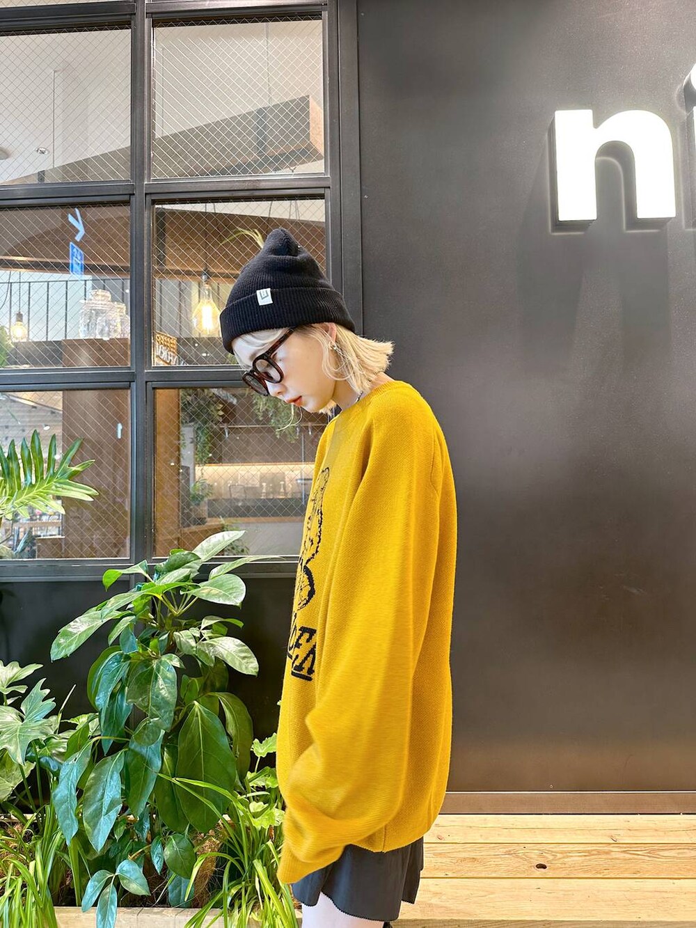 イエロー系のニット/セーター、ブラック系のスカート、ブラック系のニットキャップ/ビーニーを着用したレディースの秋コーディネートの3枚目の写真