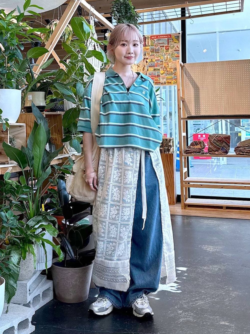 グレー系のスニーカー、グリーン系のポロシャツ、ベージュ系のショルダーバッグを着用したレディースの夏コーディネートの2枚目の写真
