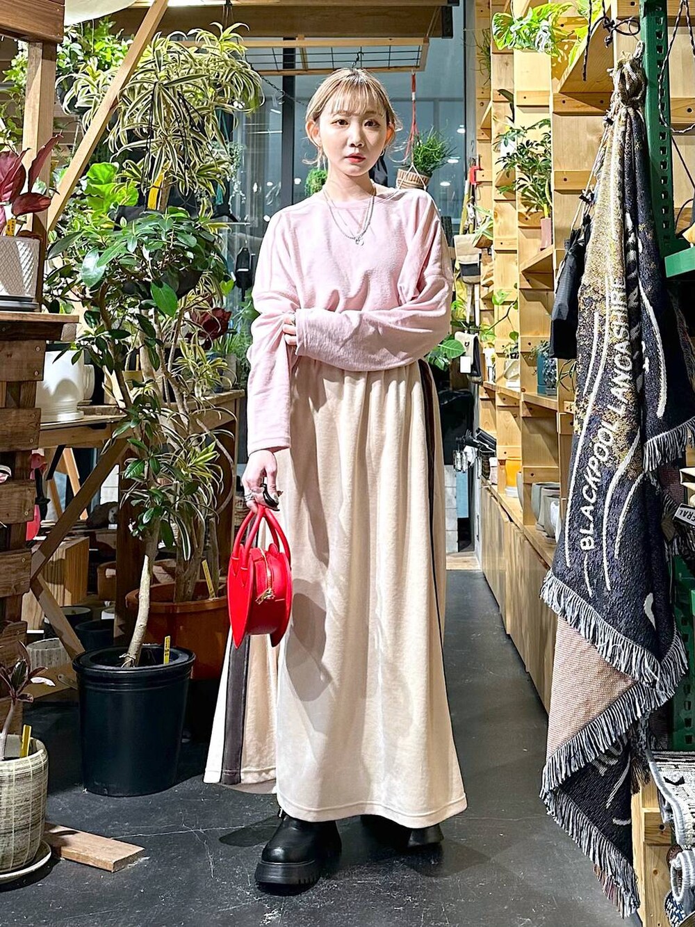 レッド系のショルダーバッグ、ブラック系のブーツ、ベージュ系のスカートを着用したレディースの冬コーディネートの3枚目の写真