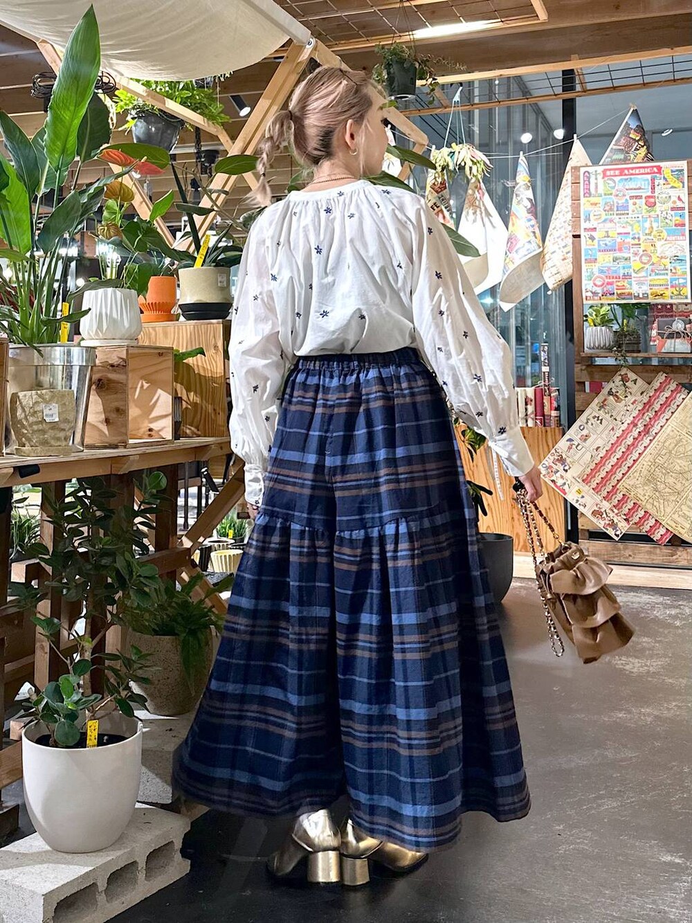 ブルー系のその他パンツ、ゴールド系のブーツ、ブラウン系のショルダーバッグを着用したレディースの夏コーディネートの2枚目の写真