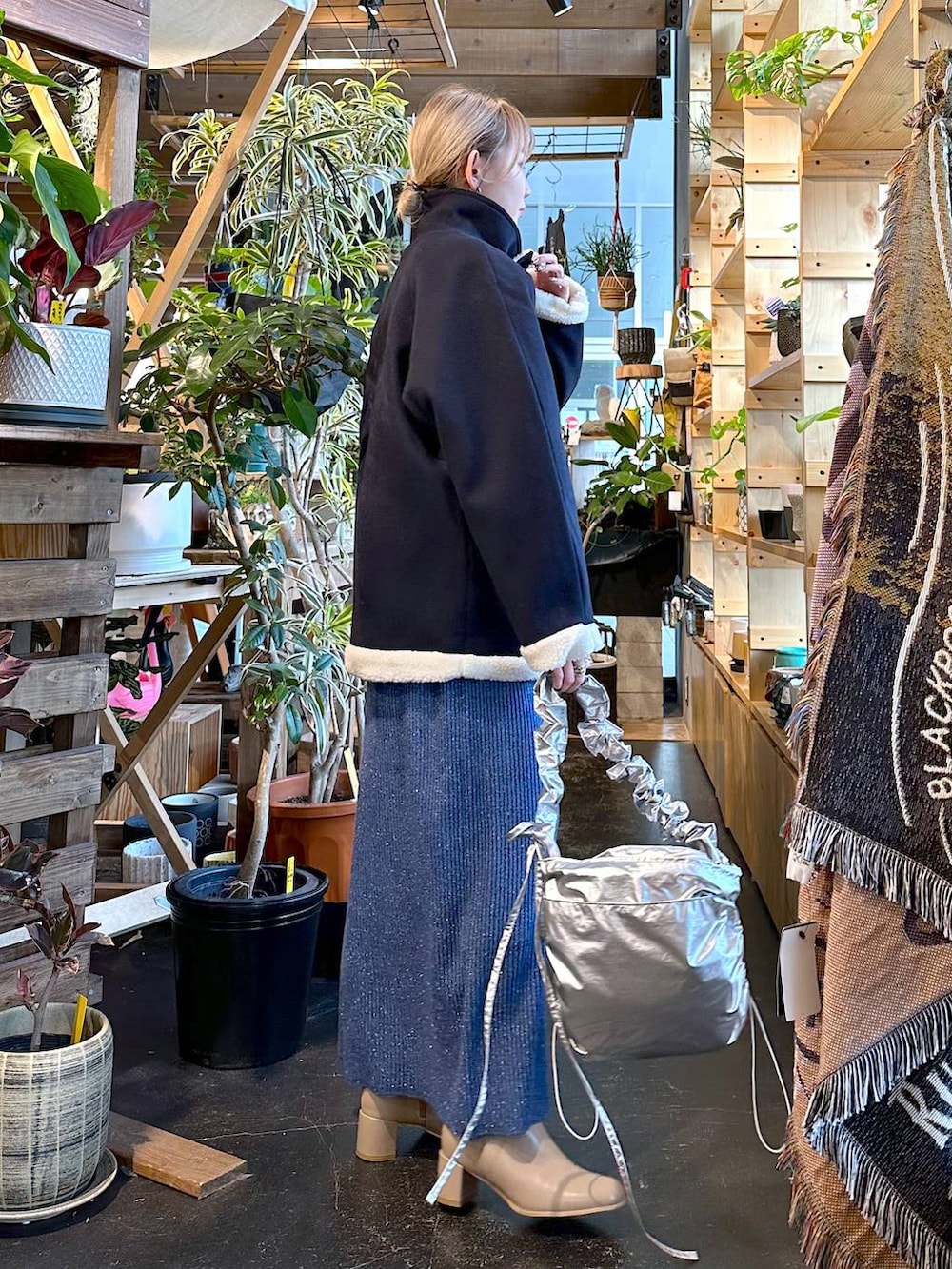 ブルー系のブルゾン、ベージュ系のブーツ、グレー系のショルダーバッグを着用したレディースの冬コーディネートの5枚目の写真