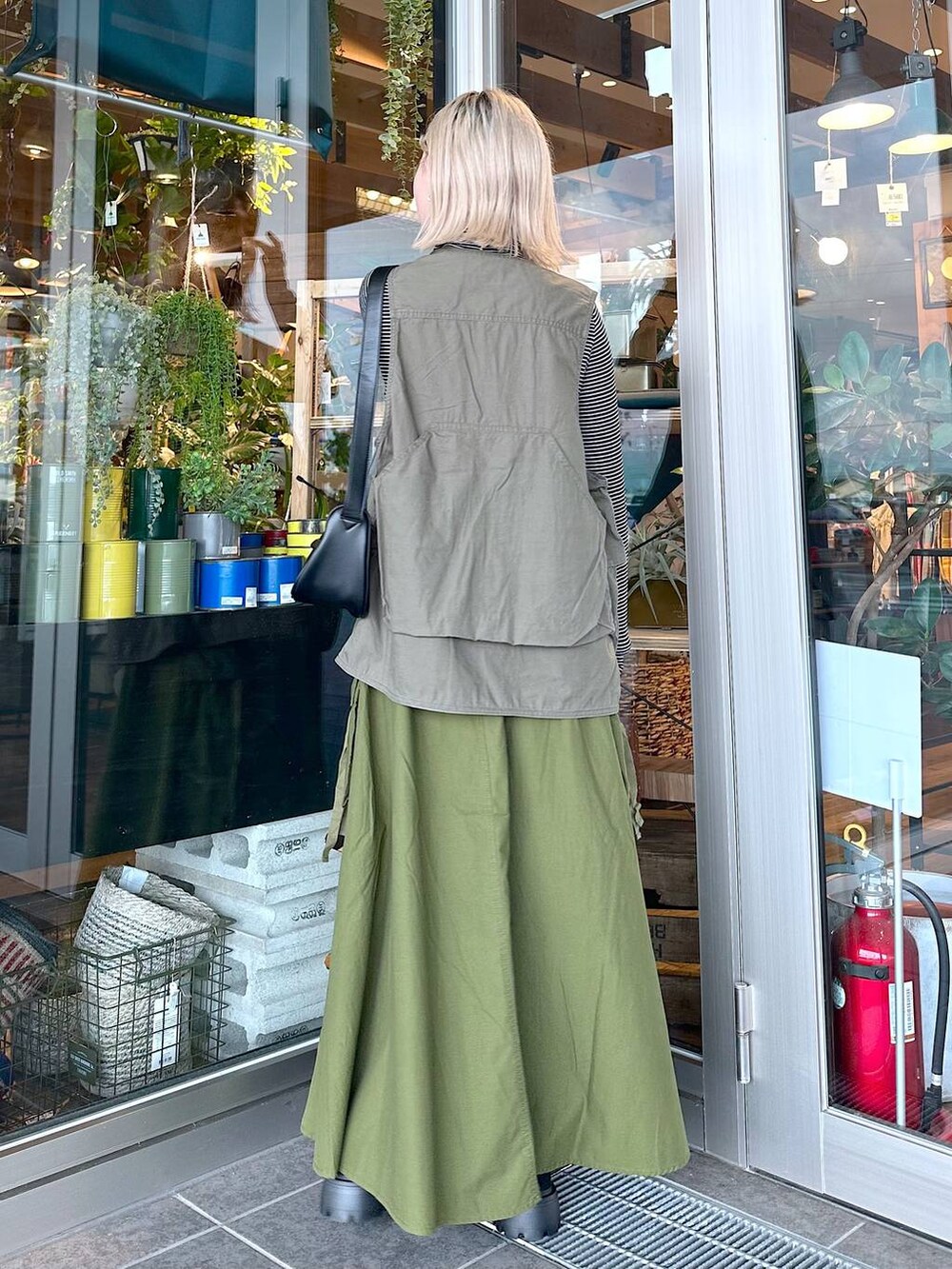 グリーン系のベスト、ブラック系のTシャツ/カットソー、ブラック系のショルダーバッグを着用したレディースの夏コーディネートの2枚目の写真