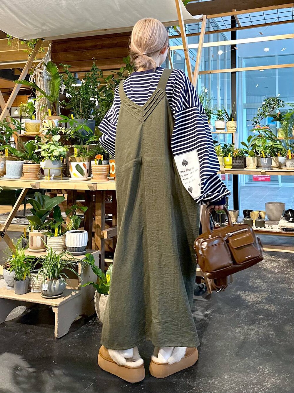 グリーン系のジャンパースカート、その他のTシャツ/カットソー、ブラウン系のショルダーバッグを着用したレディースの秋コーディネートの4枚目の写真