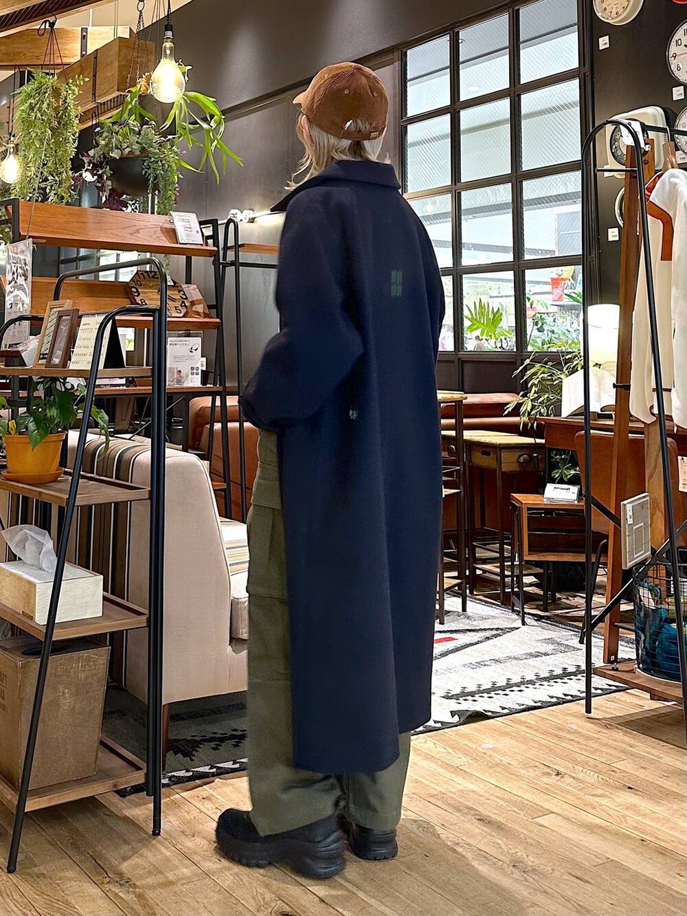 ブルー系のステンカラーコート、ブラック系のブーツ、グリーン系のその他パンツを着用したレディースの冬コーディネートの2枚目の写真