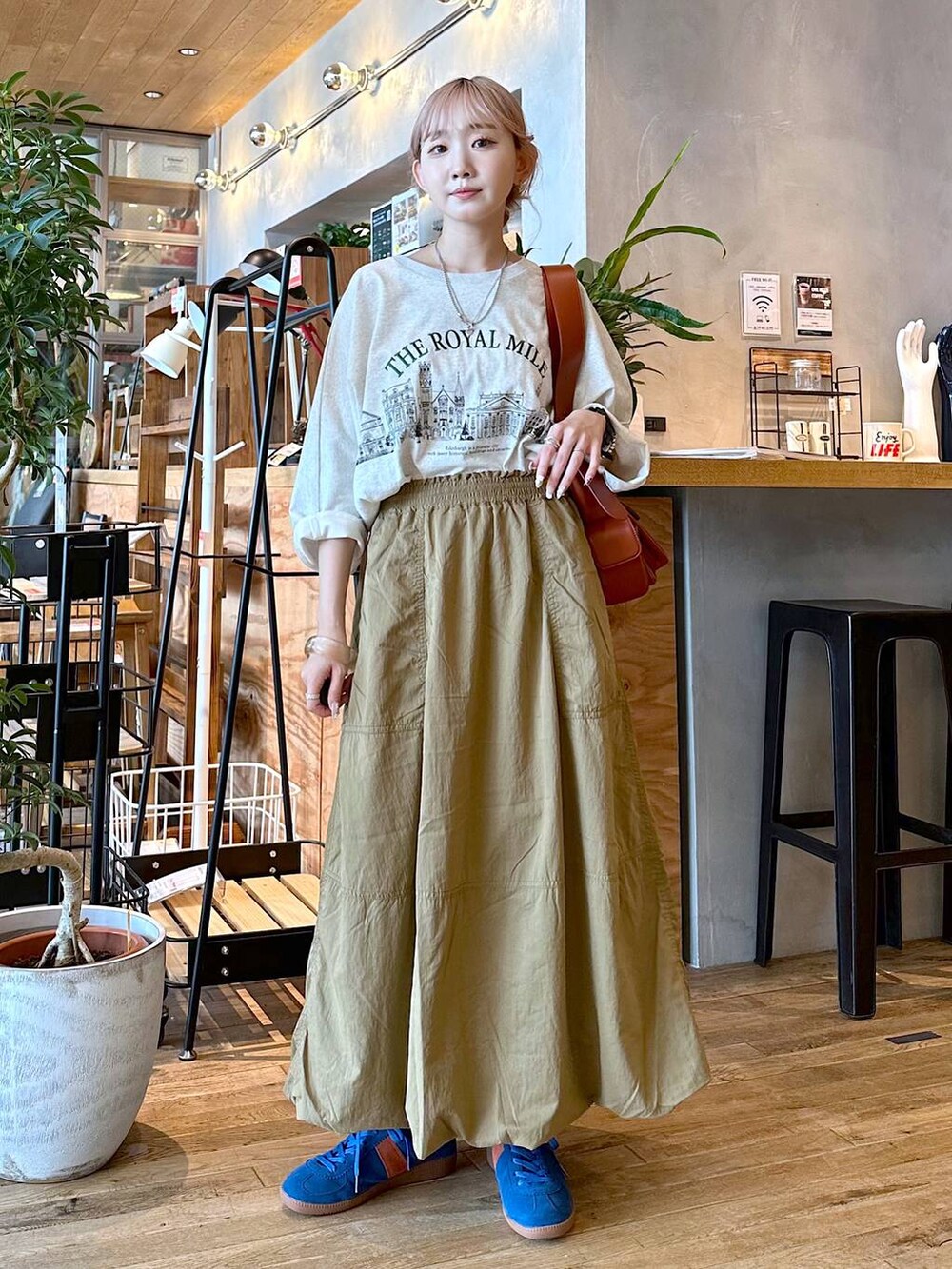 ベージュ系のTシャツ/カットソー、ブラウン系のショルダーバッグ、ブルー系のスニーカーを着用したレディースの夏コーディネートの3枚目の写真