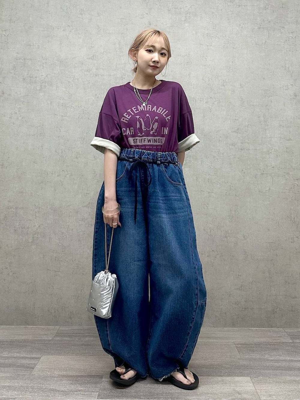 シルバー系のショルダーバッグ、パープル系のTシャツ/カットソー、ブルー系のデニムパンツを着用したレディースの春コーディネートの4枚目の写真