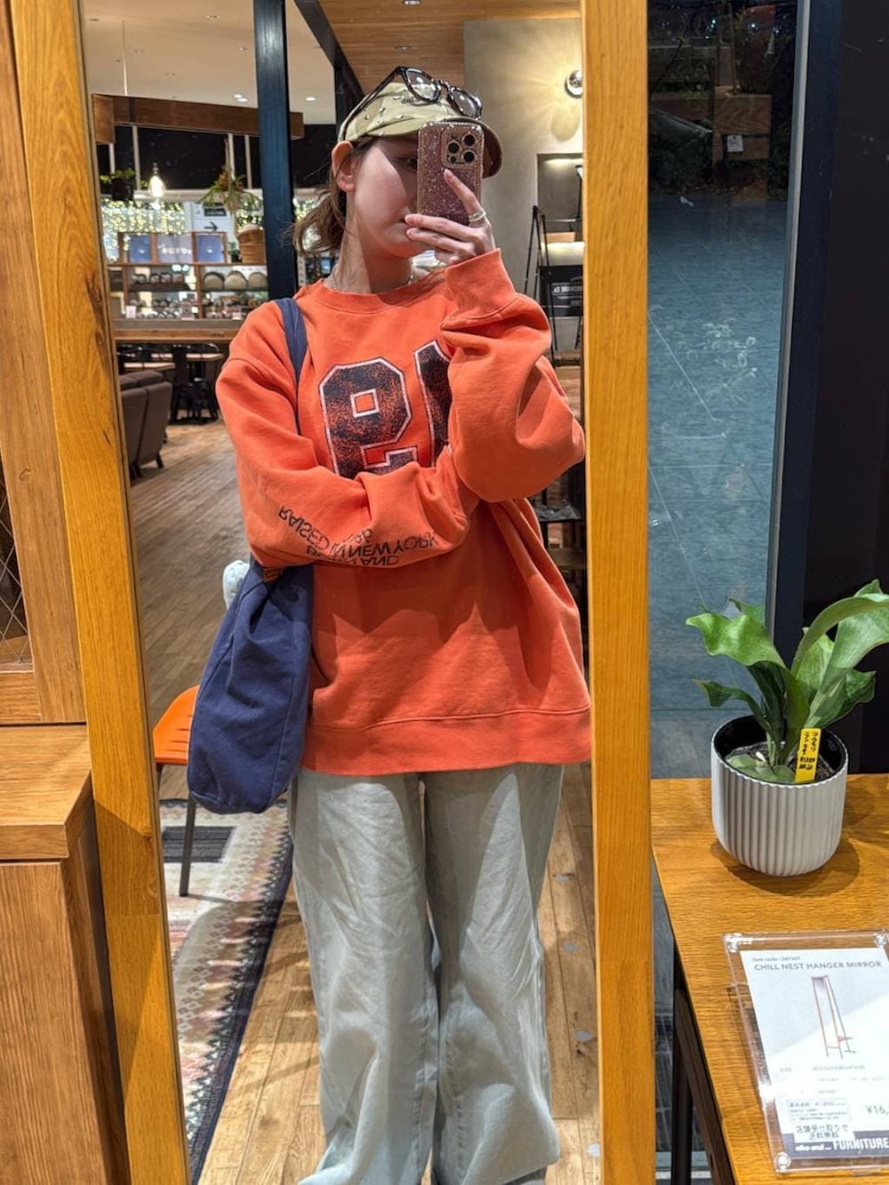 ブルー系のトートバッグ、ブルー系のデニムパンツ、オレンジ系のスウェットを着用したレディースの冬コーディネートの4枚目の写真