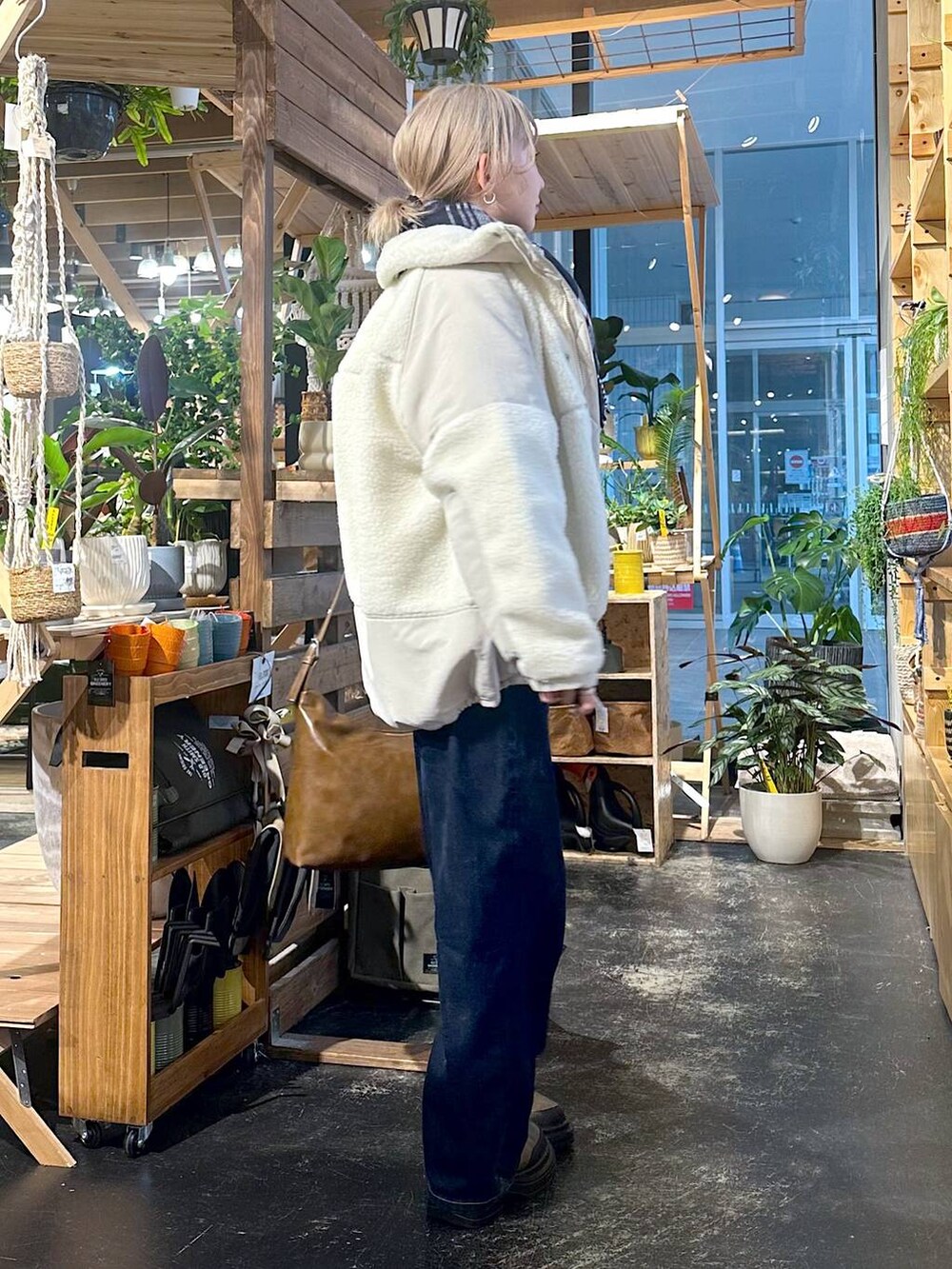 ベージュ系のブルゾン、ブルー系のデニムパンツ、ブラウン系のブーツを着用したレディースの冬コーディネートの2枚目の写真