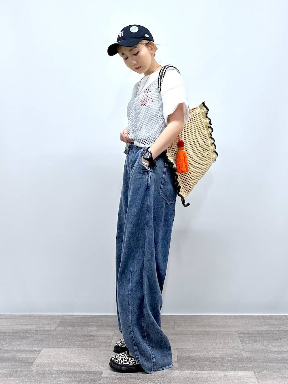 ベージュ系のトートバッグ、その他のスニーカー、ブルー系のデニムパンツを着用したレディースの夏コーディネートの3枚目の写真