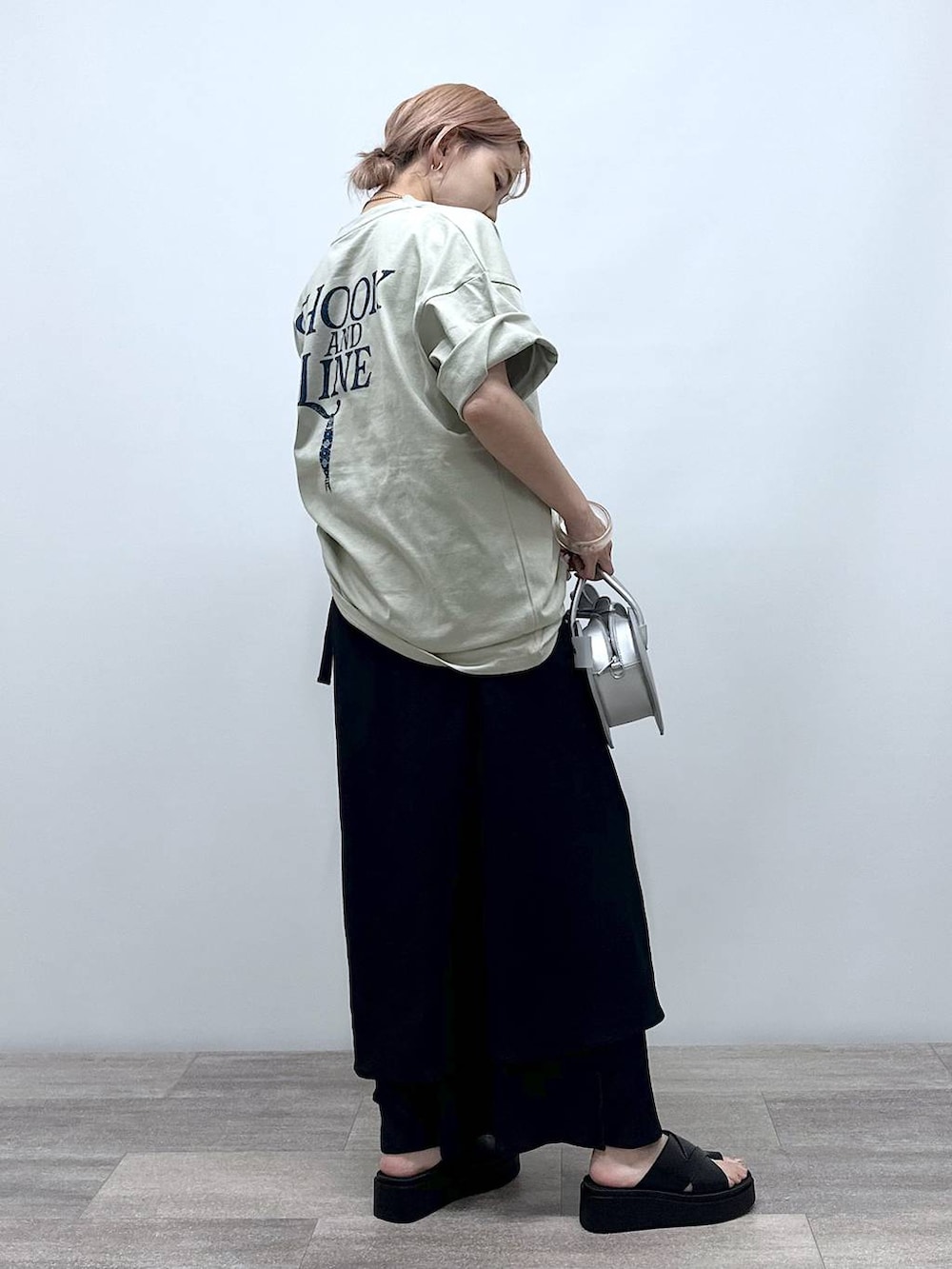 シルバー系のショルダーバッグ、ベージュ系のTシャツ/カットソー、ブラック系のサンダルを着用したレディースの夏コーディネートの4枚目の写真