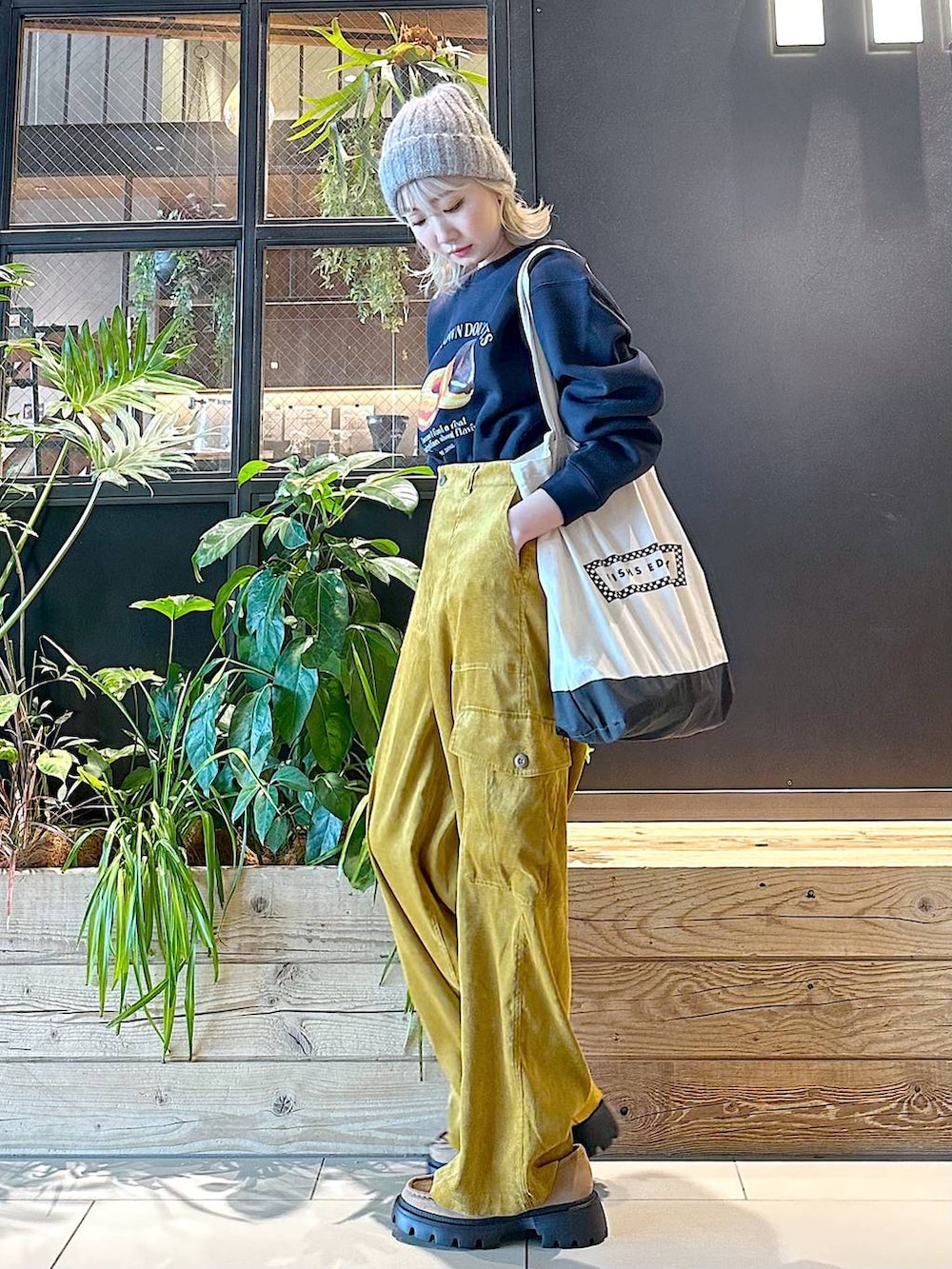 ブラック系のトートバッグ、イエロー系のモカシン/デッキシューズ、イエロー系のカーゴパンツを着用したレディースの秋コーディネートの2枚目の写真