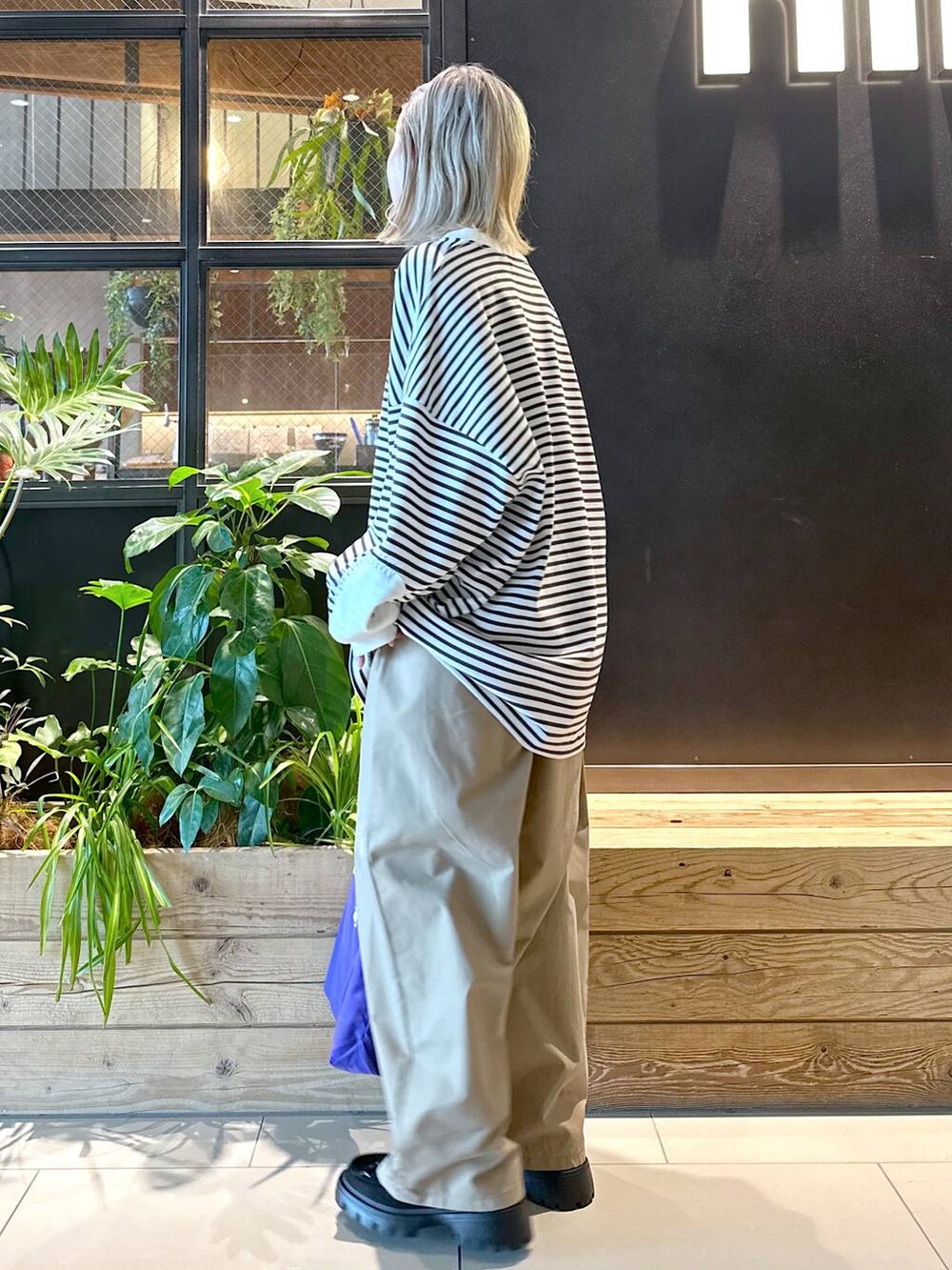 パープル系のトートバッグ、イエロー系のチノパンツ、ブラック系のモカシン/デッキシューズを着用したレディースの秋コーディネートの3枚目の写真