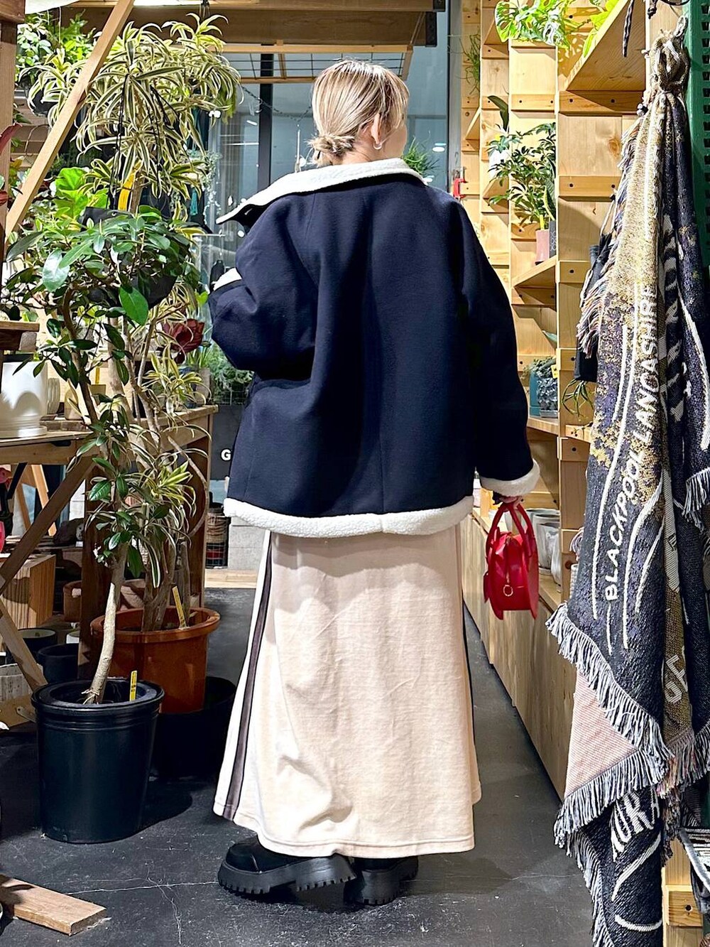 レッド系のショルダーバッグ、ブルー系のブルゾン、ブラック系のブーツを着用したレディースの冬コーディネートの3枚目の写真