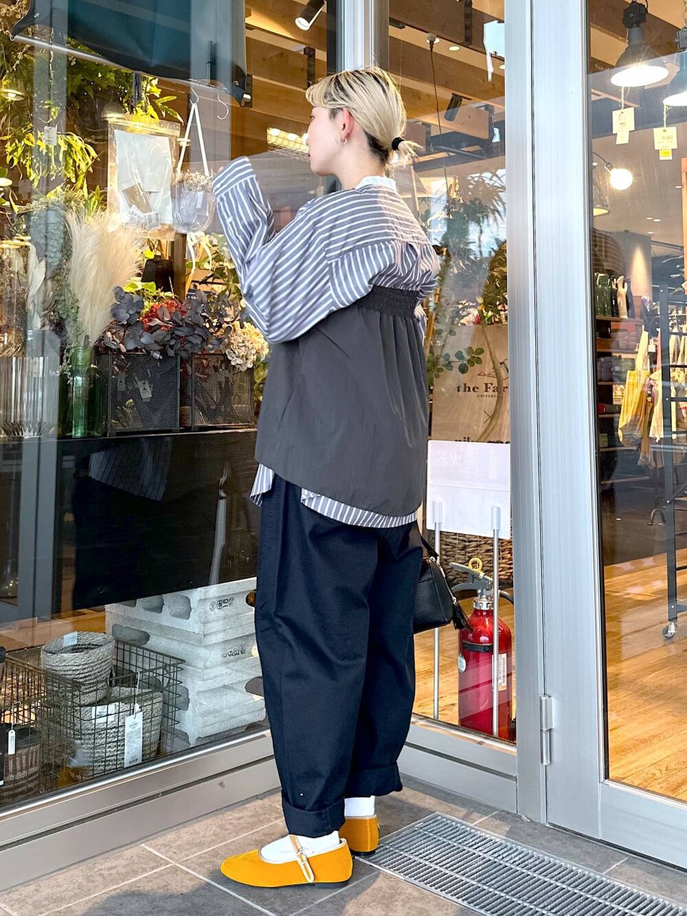 イエロー系のパンプス、グレー系のシャツ/ブラウス、ブルー系のチノパンツを着用したレディースの秋コーディネートの3枚目の写真