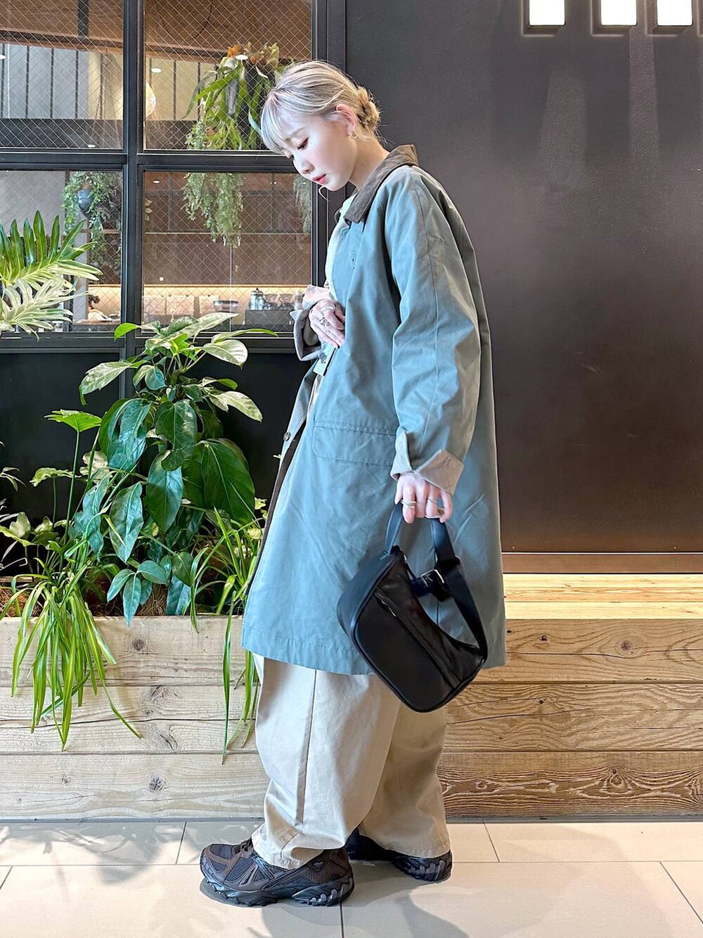 ブラック系のショルダーバッグ、ブラウン系のスニーカー、イエロー系のチノパンツを着用したレディースの秋コーディネートの3枚目の写真