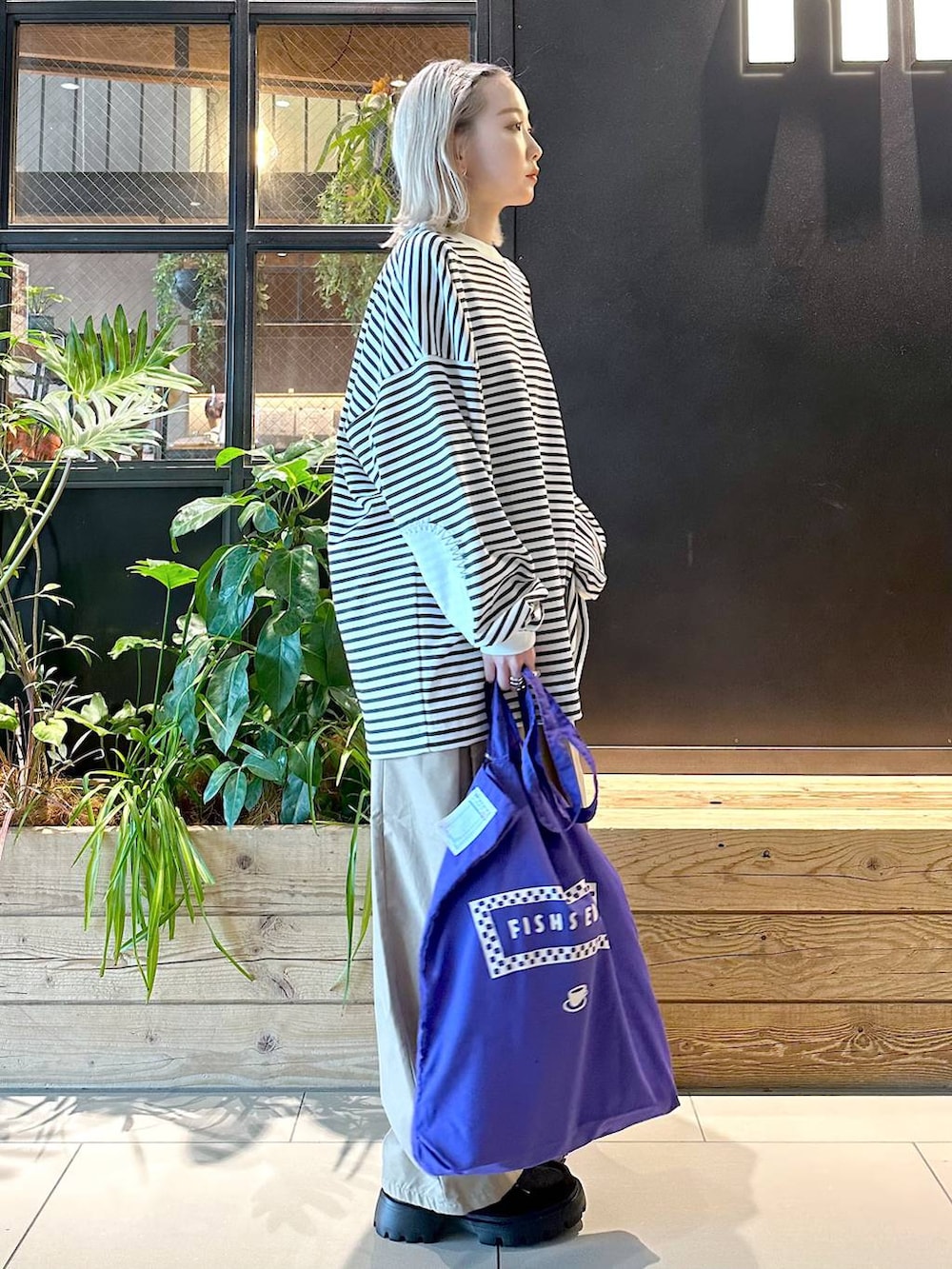 パープル系のトートバッグ、イエロー系のチノパンツ、ブラック系のモカシン/デッキシューズを着用したレディースの秋コーディネートの4枚目の写真