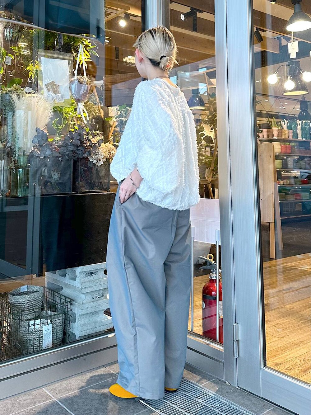 イエロー系のパンプス、グリーン系のチノパンツ、ブラック系のショルダーバッグを着用したレディースの秋コーディネートの2枚目の写真