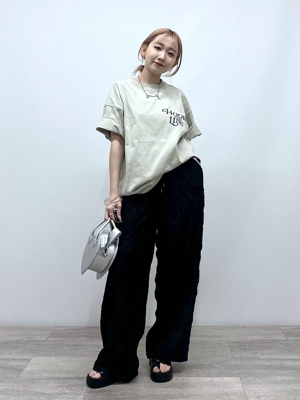 シルバー系のショルダーバッグ、ベージュ系のTシャツ/カットソー、ブラック系のその他パンツを着用したレディースの春コーディネートの4枚目の写真