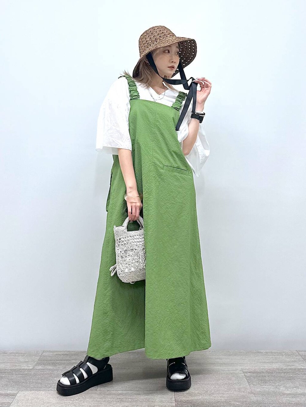 グレー系のショルダーバッグ、ブラック系のサンダル、グリーン系のジャンパースカートを着用したレディースの夏コーディネートの2枚目の写真