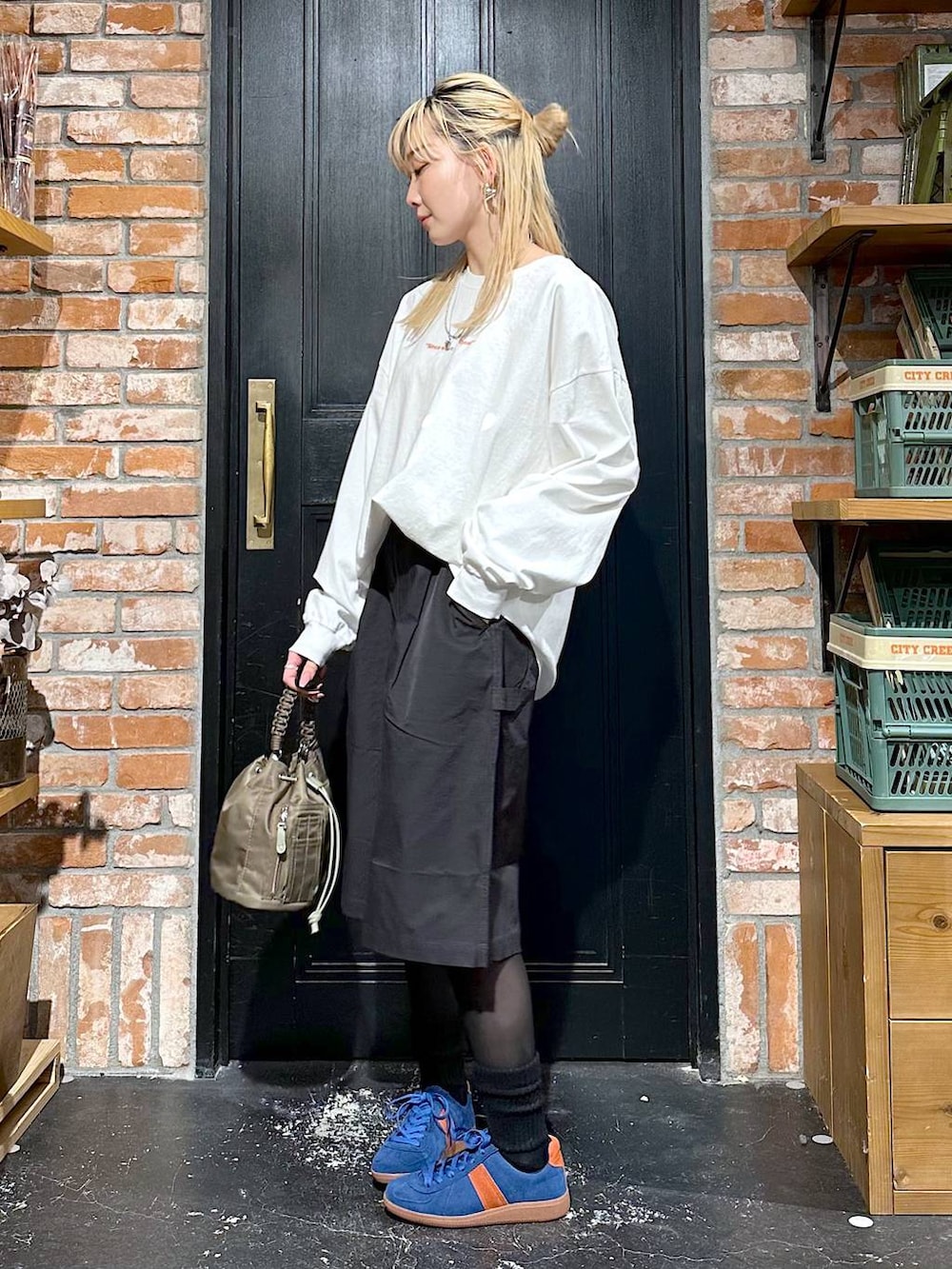 ブルー系のスニーカー、グリーン系のショルダーバッグ、その他のTシャツ/カットソーを着用したレディースの冬コーディネートの2枚目の写真