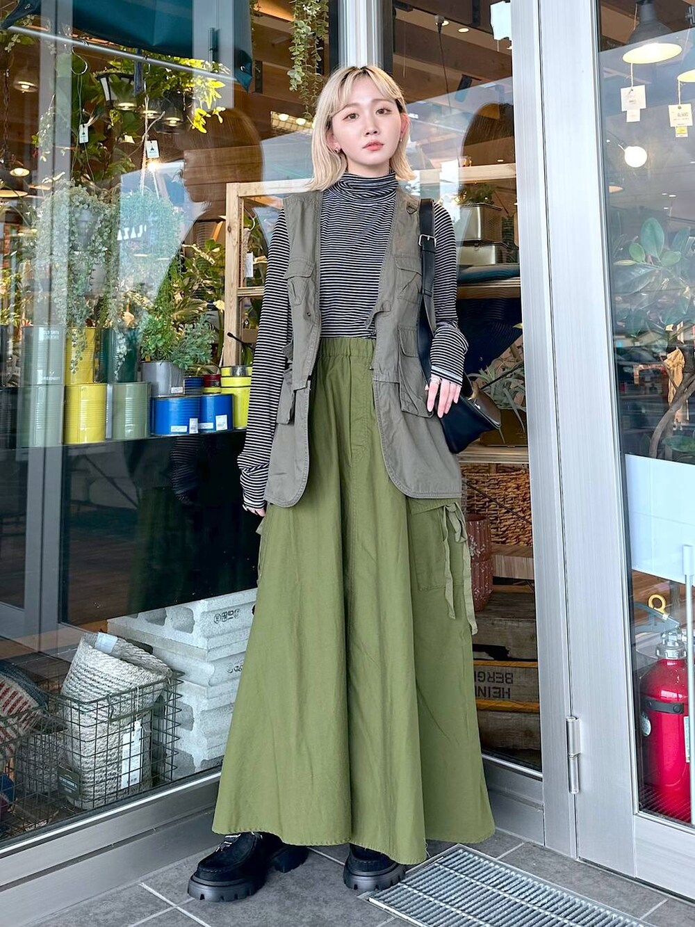 グリーン系のベスト、ブラック系のTシャツ/カットソー、ブラック系のショルダーバッグを着用したレディースの夏コーディネートの3枚目の写真