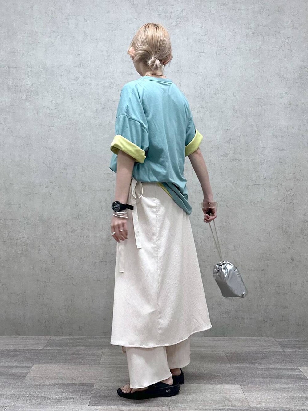 シルバー系のショルダーバッグ、グリーン系のTシャツ/カットソー、ブラック系のサンダルを着用したレディースの春コーディネートの2枚目の写真