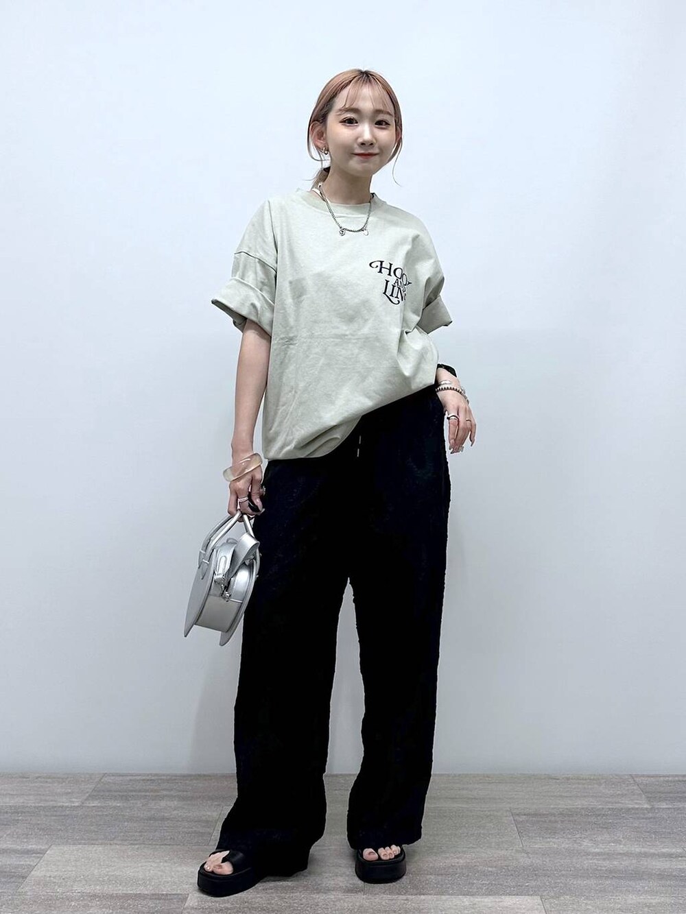 シルバー系のショルダーバッグ、ベージュ系のTシャツ/カットソー、ブラック系のその他パンツを着用したレディースの春コーディネートの3枚目の写真