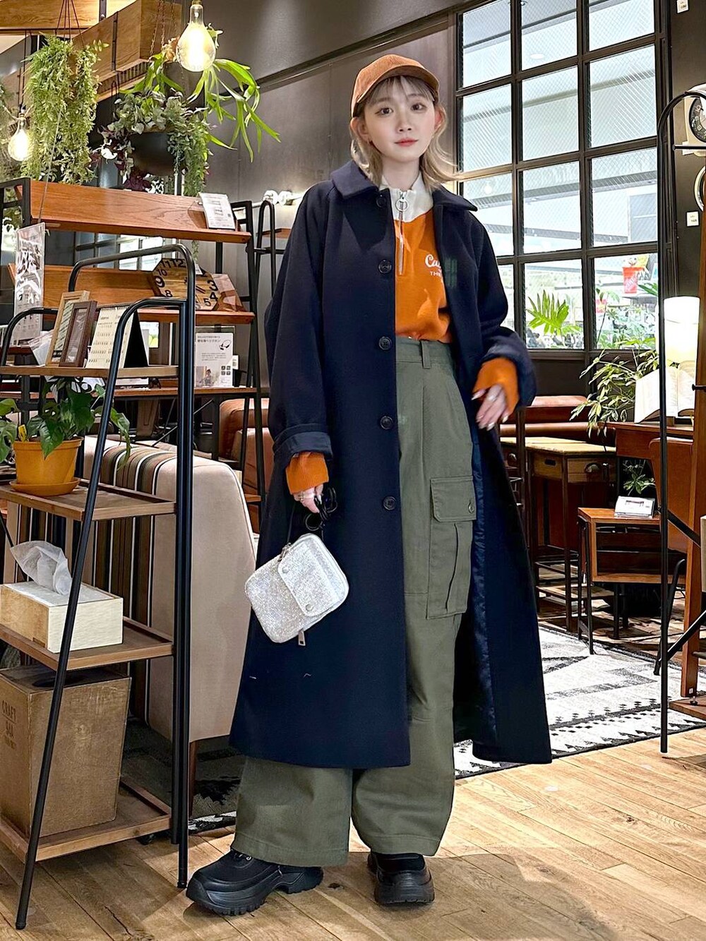 ブルー系のステンカラーコート、ブラック系のブーツ、グリーン系のその他パンツを着用したレディースの冬コーディネートの4枚目の写真