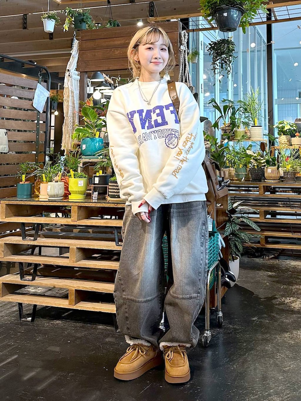 ブラウン系のデニムパンツ、イエロー系のモカシン/デッキシューズ、ブラウン系のショルダーバッグを着用したレディースの秋コーディネートの3枚目の写真