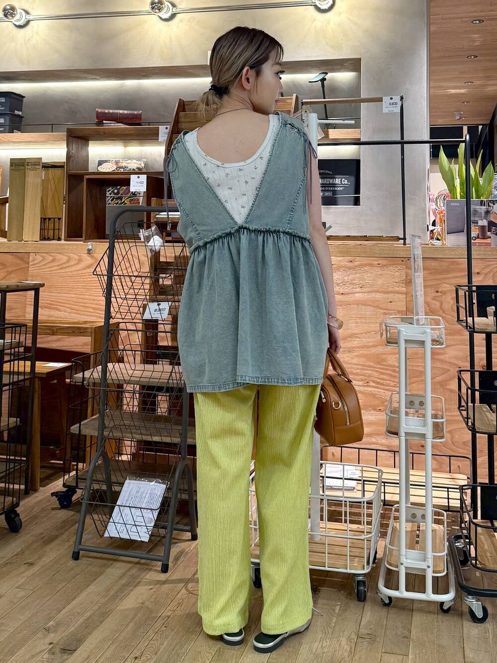 ブルー系のベスト、ホワイト系のタンクトップ、イエロー系のボストンバッグを着用したレディースの夏コーディネートの2枚目の写真