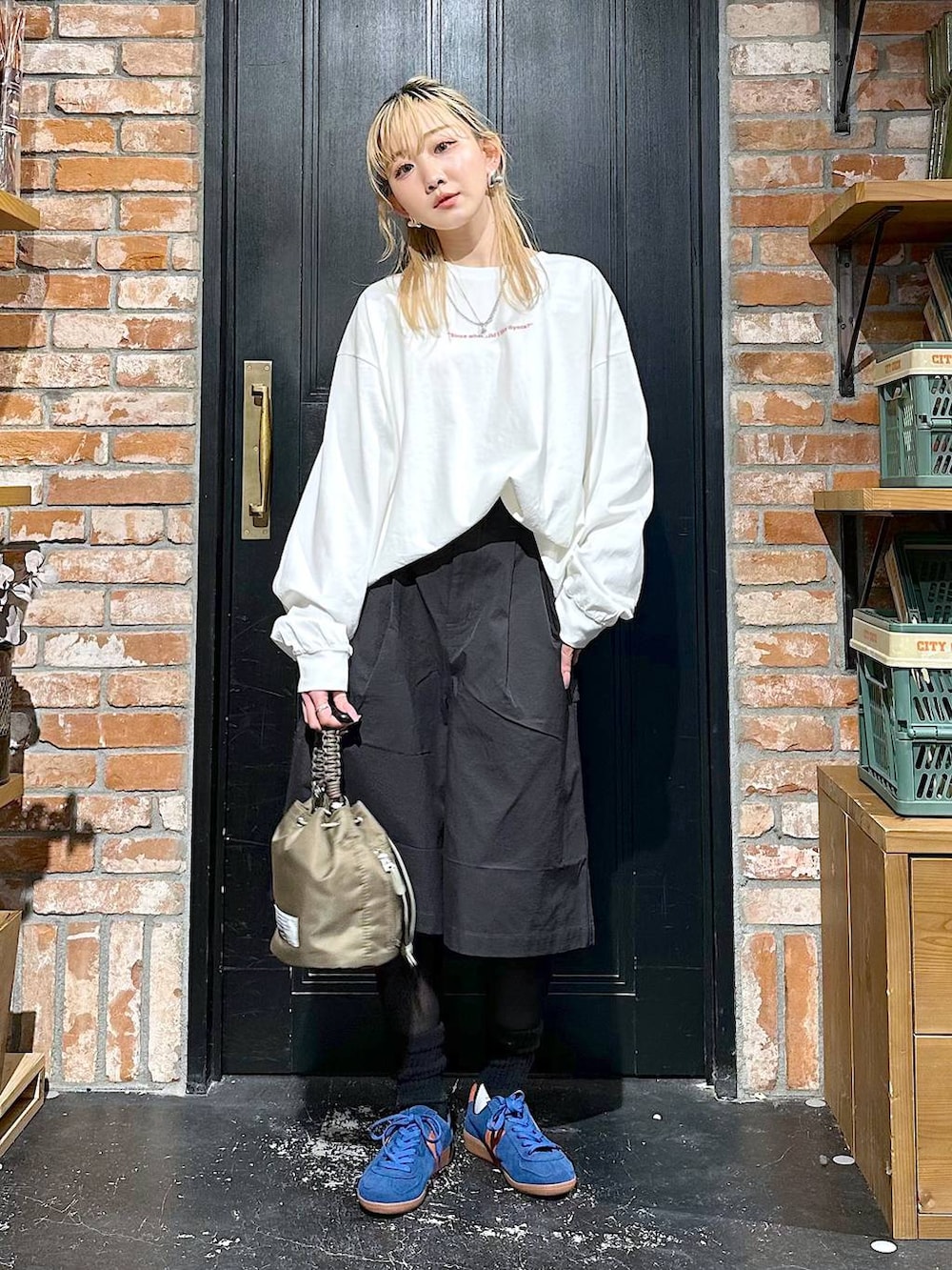 ブルー系のスニーカー、グリーン系のショルダーバッグ、その他のTシャツ/カットソーを着用したレディースの冬コーディネートの4枚目の写真