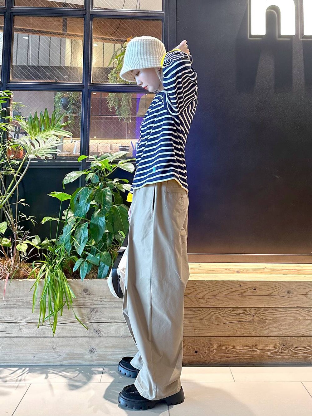 イエロー系のチノパンツ、ブラック系のモカシン/デッキシューズ、ベージュ系のショルダーバッグを着用したレディースの秋コーディネートの2枚目の写真