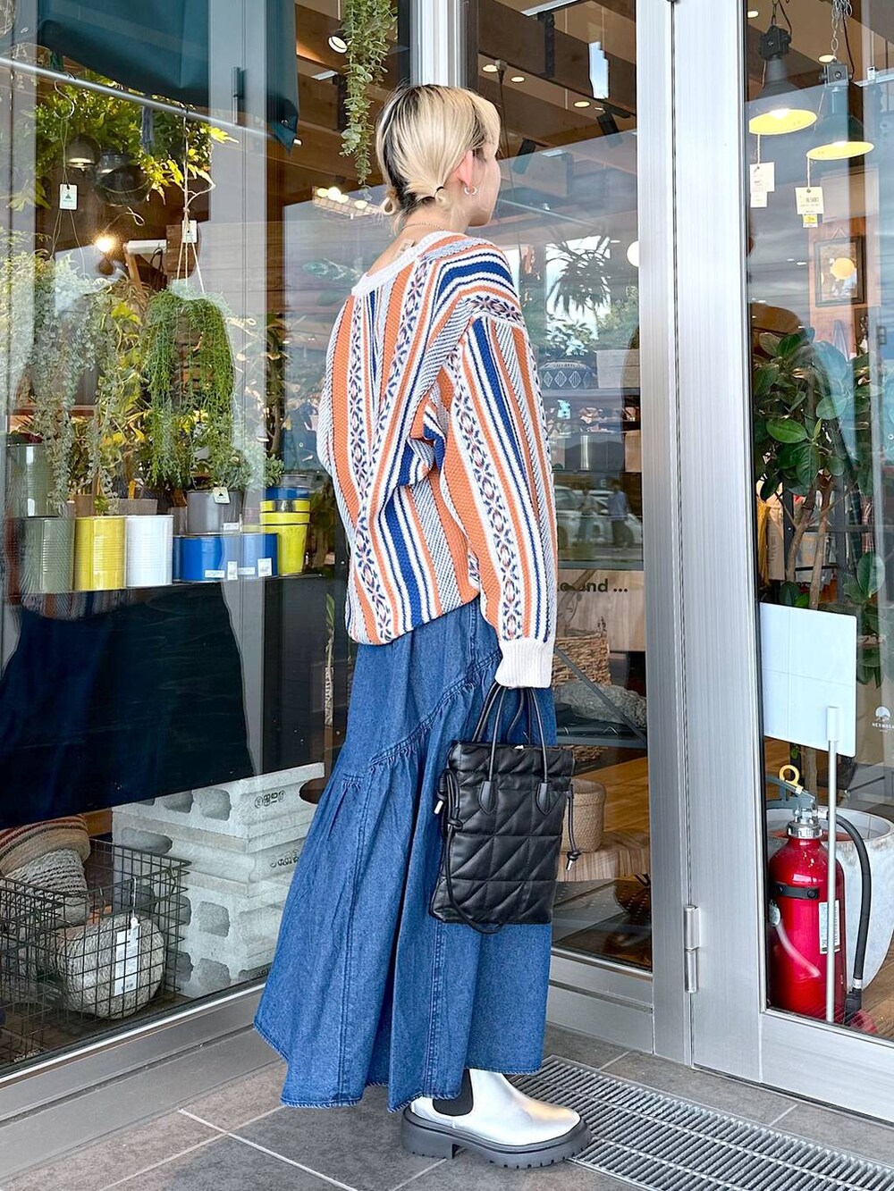 ブラック系のショルダーバッグ、ブラック系のキャミソール、オレンジ系のカーディガン/ボレロを着用したレディースの秋コーディネートの2枚目の写真