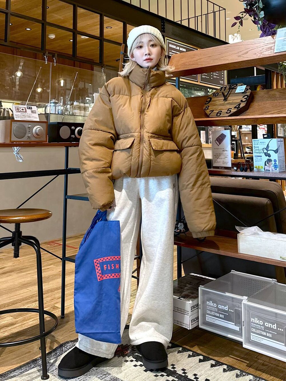 ブルー系のトートバッグ、ブラック系のブーツ、ホワイト系のその他トップスを着用したレディースの秋コーディネートの2枚目の写真