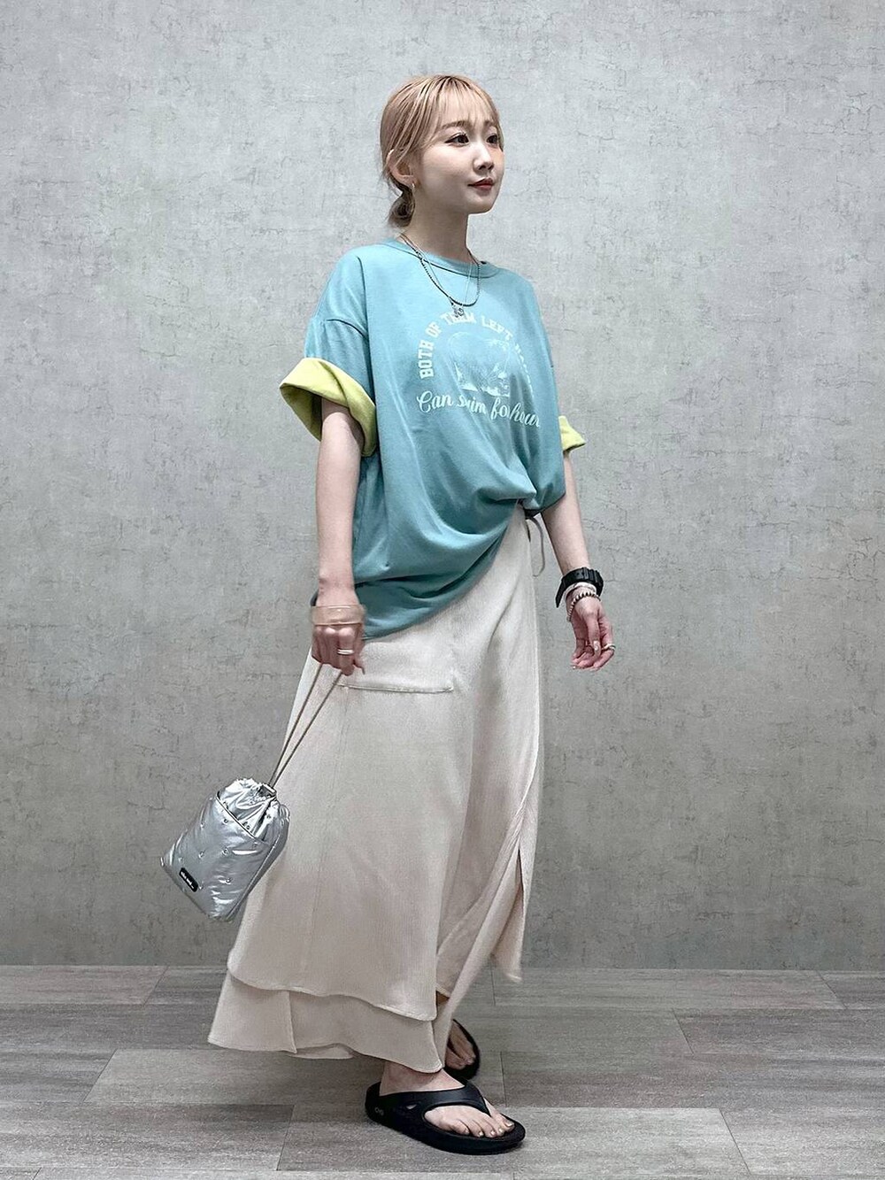 シルバー系のショルダーバッグ、グリーン系のTシャツ/カットソー、ブラック系のサンダルを着用したレディースの春コーディネートの3枚目の写真